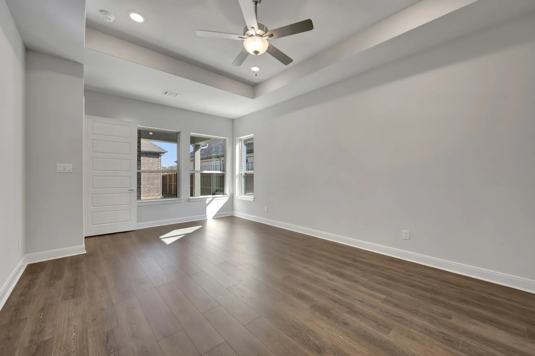Unfurnished room featuring ceiling fan, a raised ceiling, dark wood finished floors, and recessed lighting