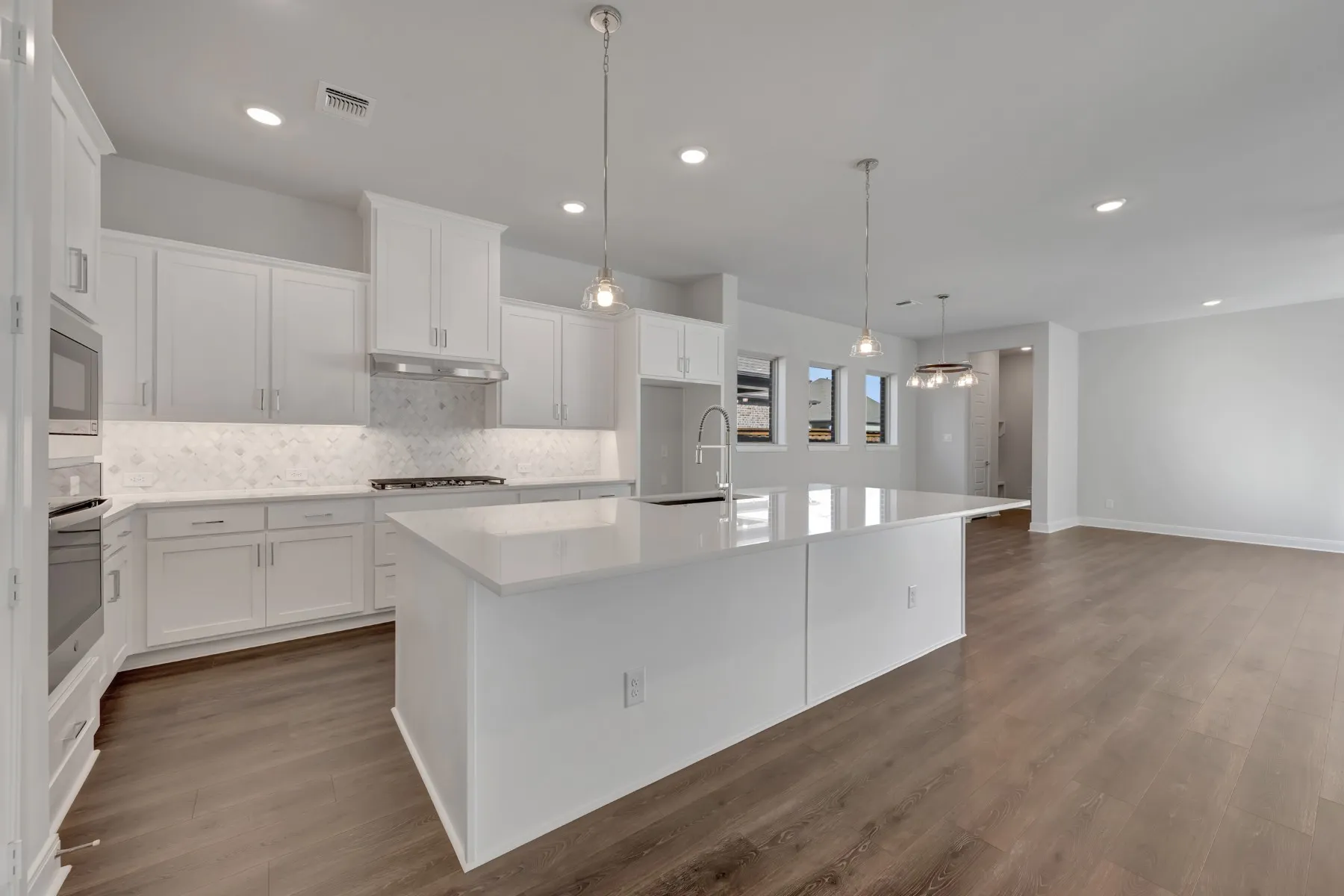 Kitchen with white cabinets, a kitchen island with sink, dark wood-style flooring, and hanging light fixtures