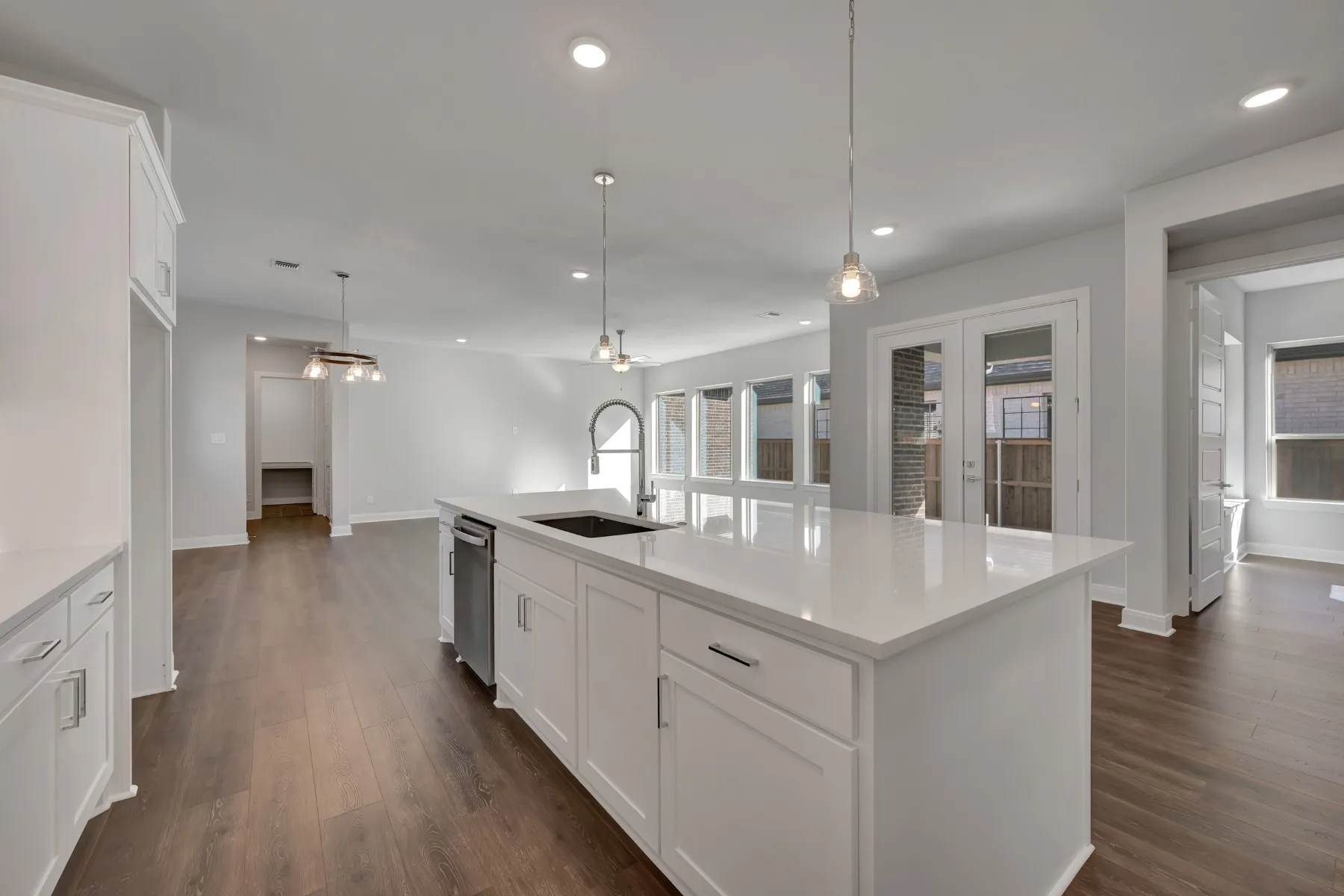 Kitchen with white cabinets, pendant lighting, a center island with sink, and dark wood-style floors