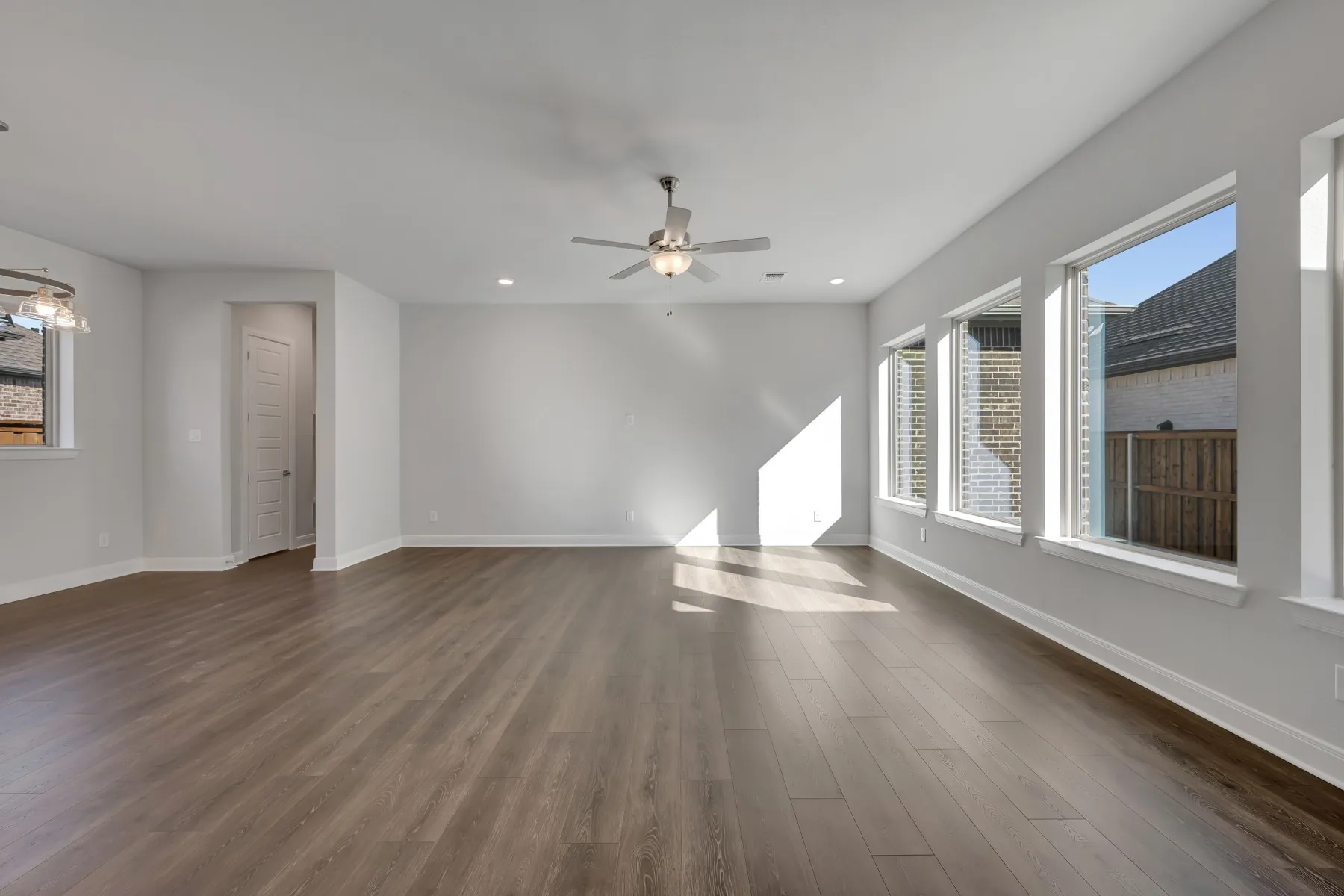 Unfurnished living room featuring dark wood-style floors, ceiling fan, and recessed lighting