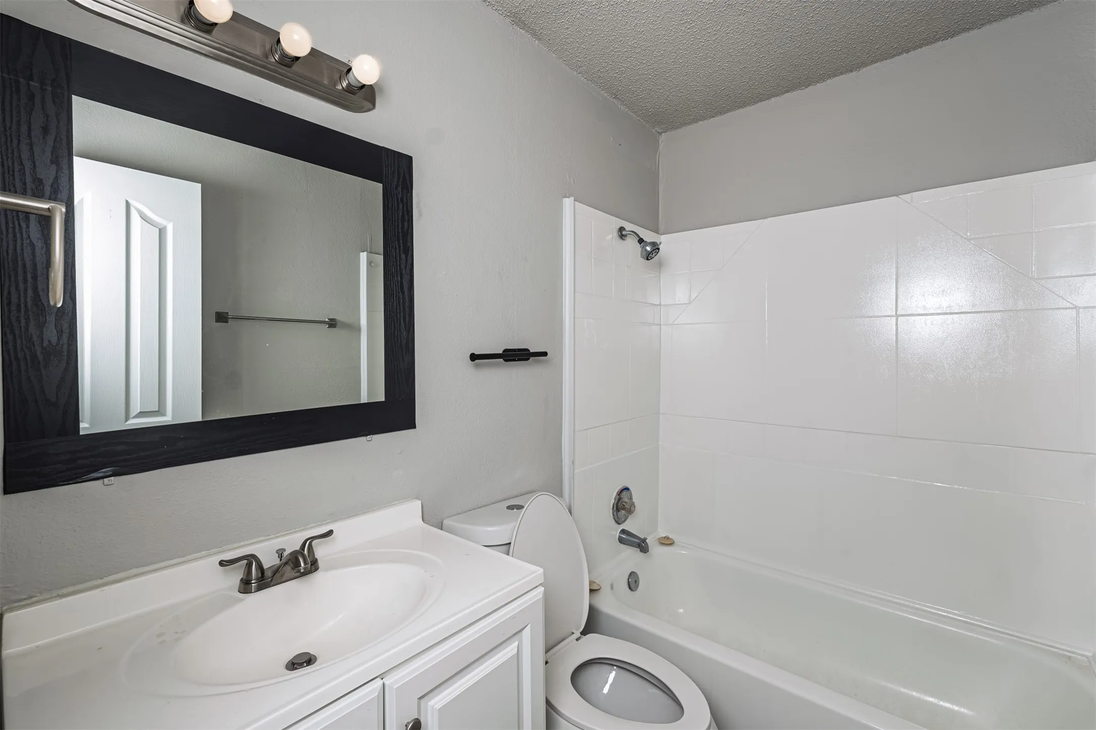 Bathroom featuring shower / bathtub combination, a textured ceiling, and vanity