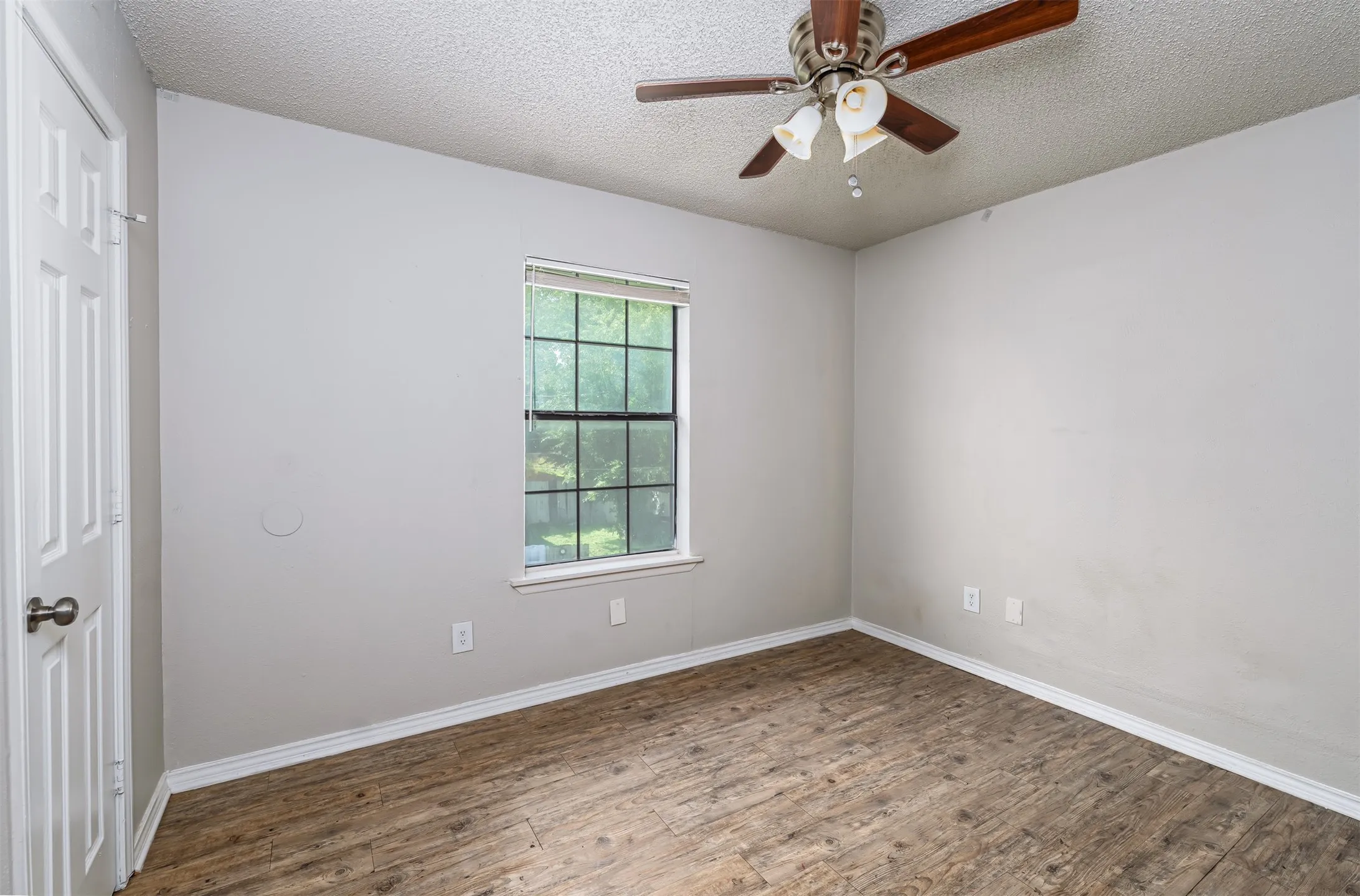 Unfurnished bedroom featuring wood finished floors, a textured ceiling, ceiling fan, and a closet