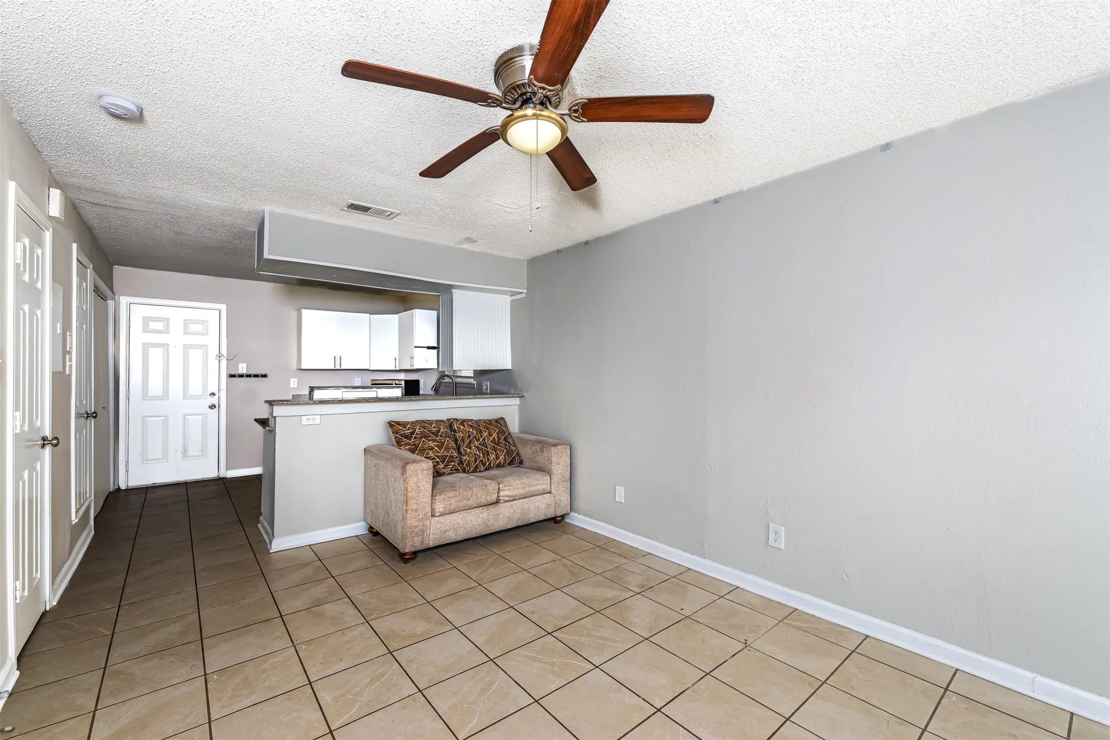 Living room featuring a textured ceiling, light tile patterned floors, and a ceiling fan