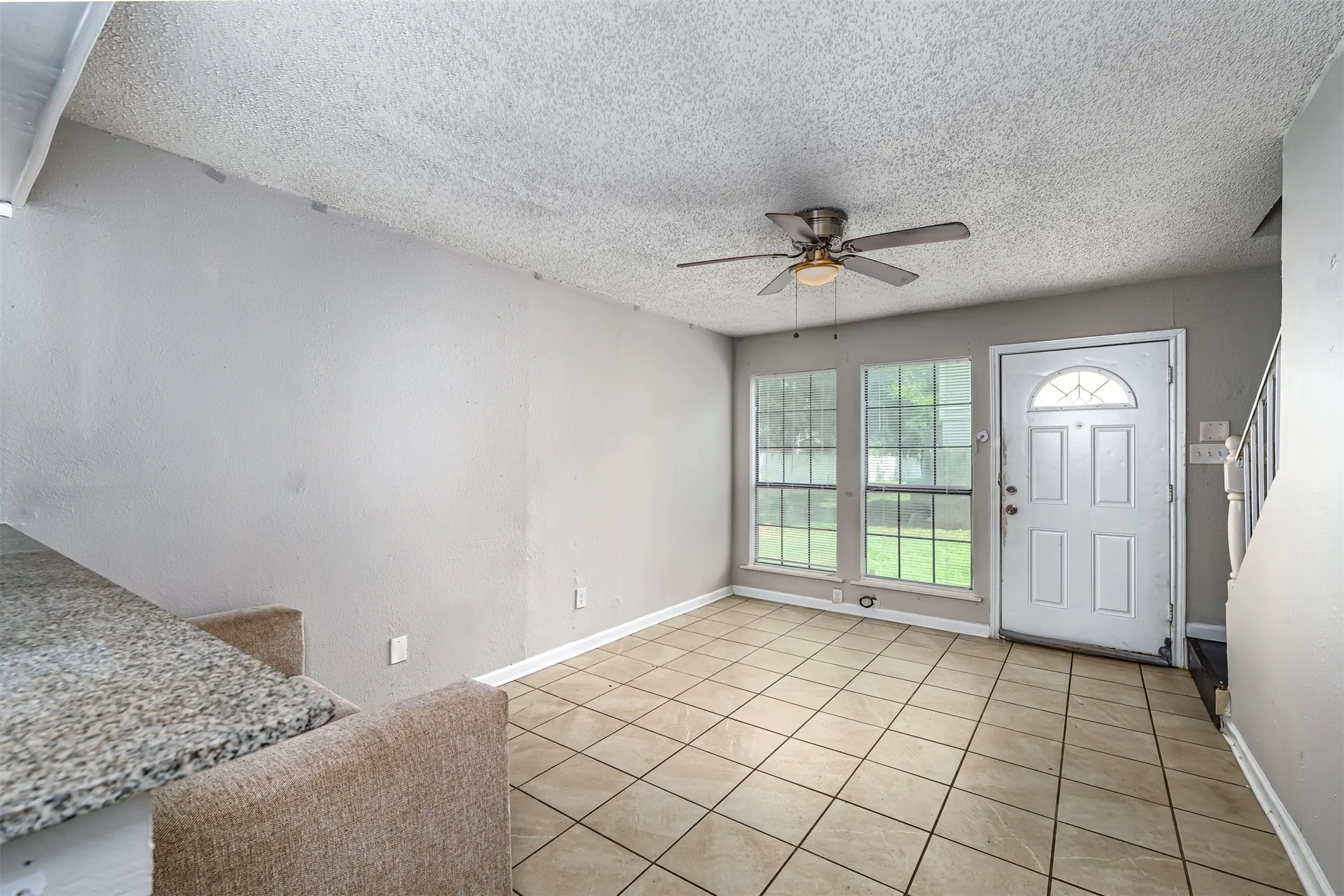 Foyer entrance with stairway, light tile patterned flooring, ceiling fan, and a textured ceiling