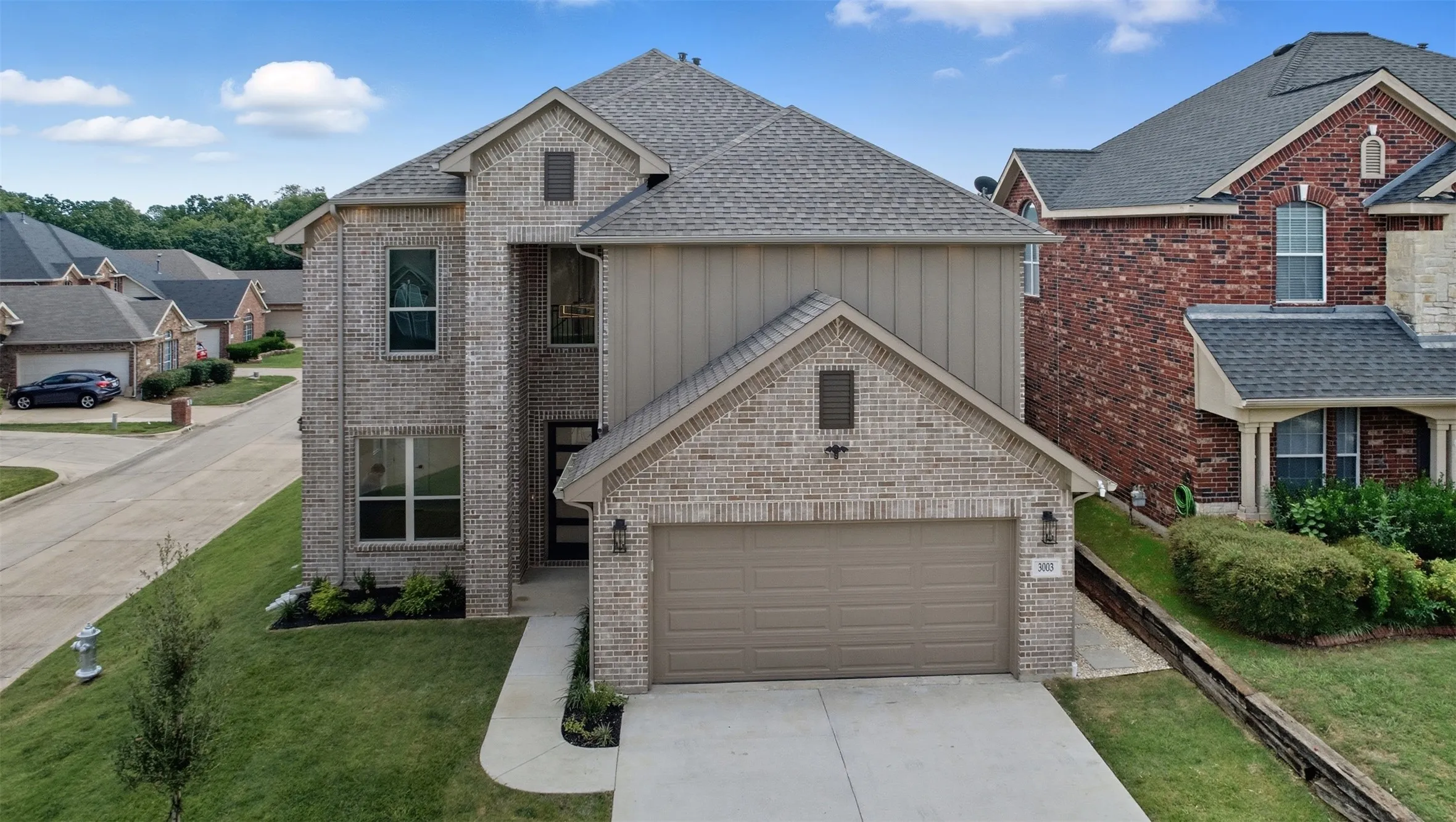 Traditional-style home featuring driveway, brick siding, a garage, and a front yard