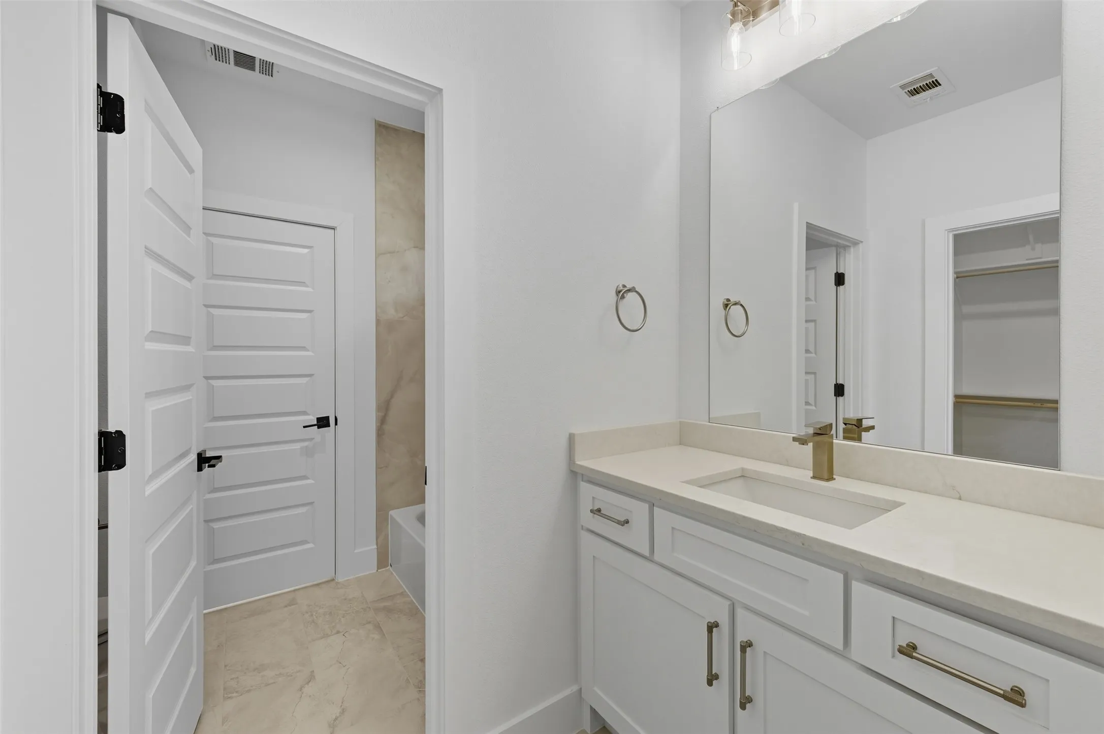 Full bathroom featuring vanity, shower / bath combination, a spacious closet, and light marble finish flooring