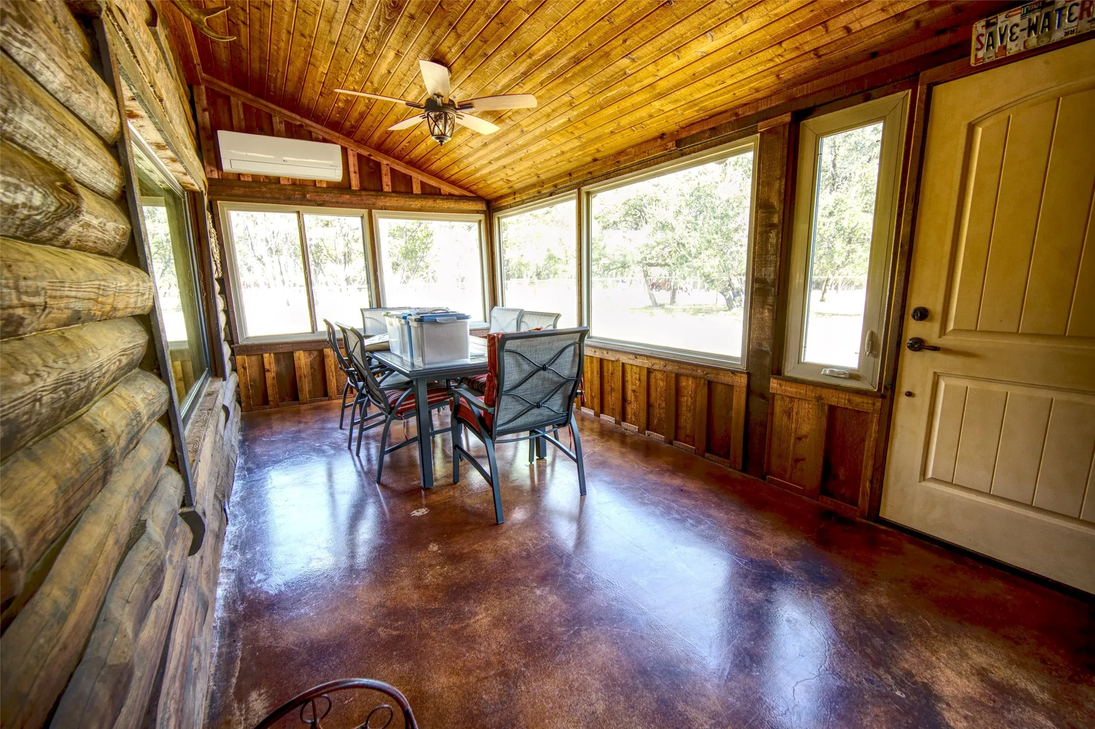 Sunroom / solarium with lofted ceiling, concrete floors, wooden ceiling, wooden walls, and an AC wall unit