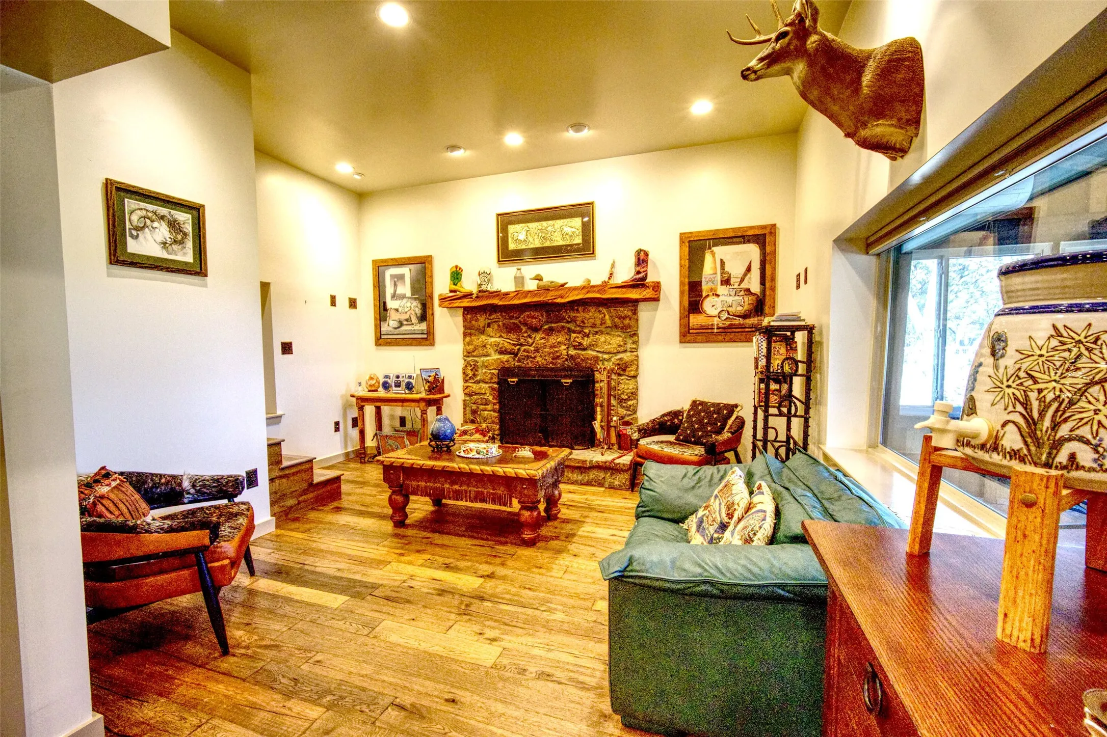 Living room with recessed lighting, light wood-style floors, and a stone fireplace