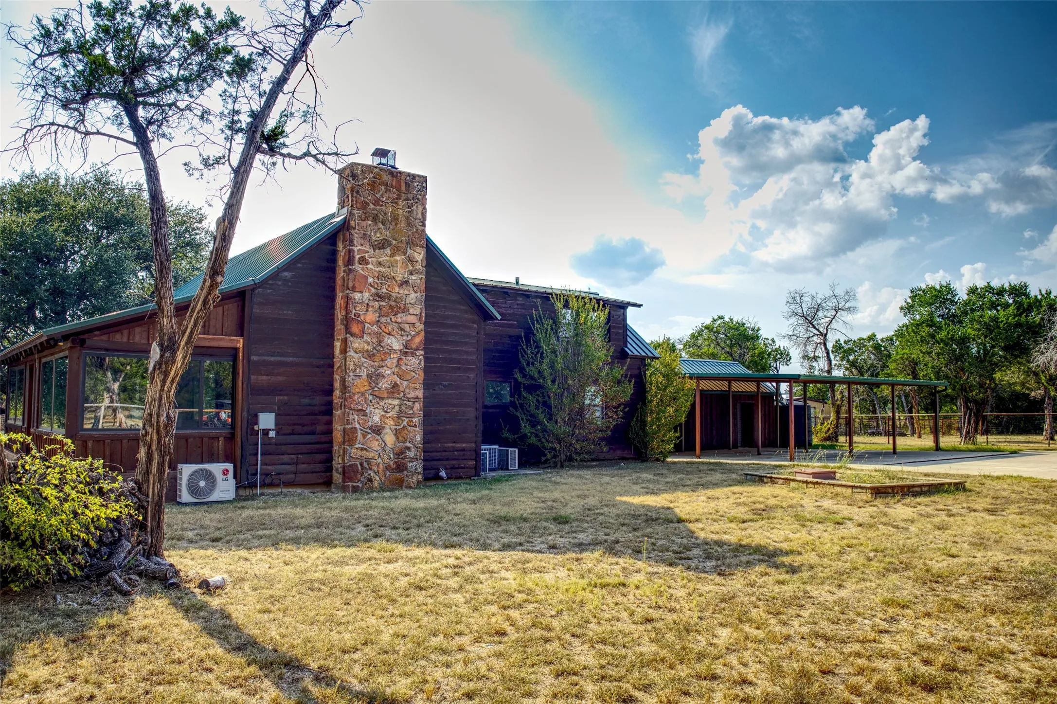 View of home's exterior featuring a chimney, a yard, a metal roof, and a carport