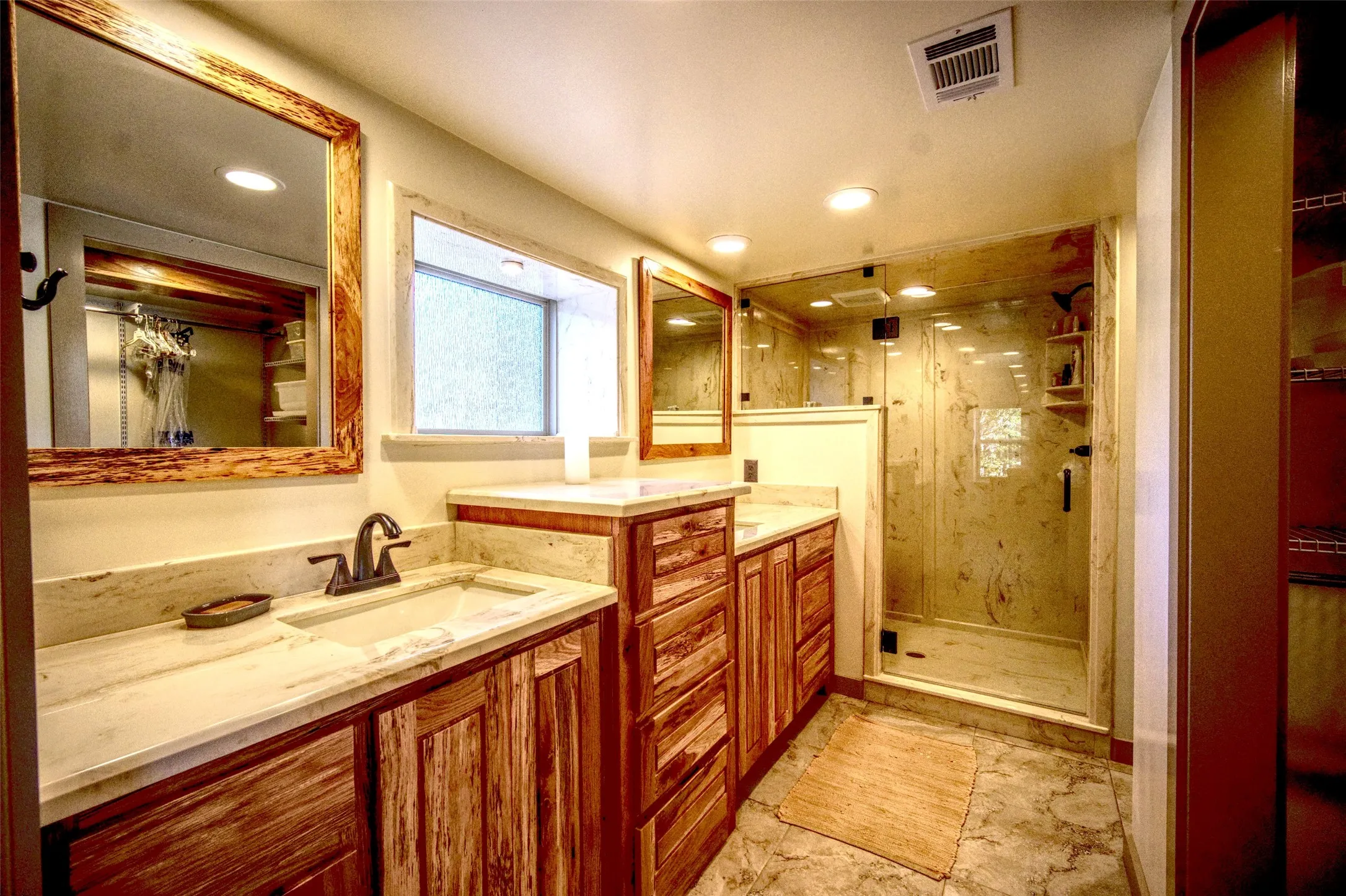 Full bath featuring a stall shower, two vanities, and recessed lighting