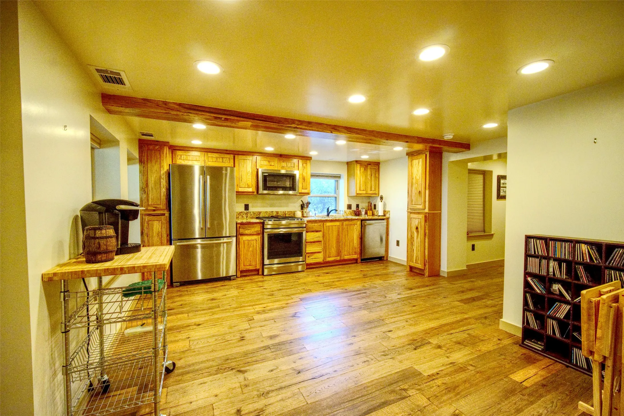 Kitchen with appliances with stainless steel finishes, light countertops, recessed lighting, light wood-type flooring, and beamed ceiling