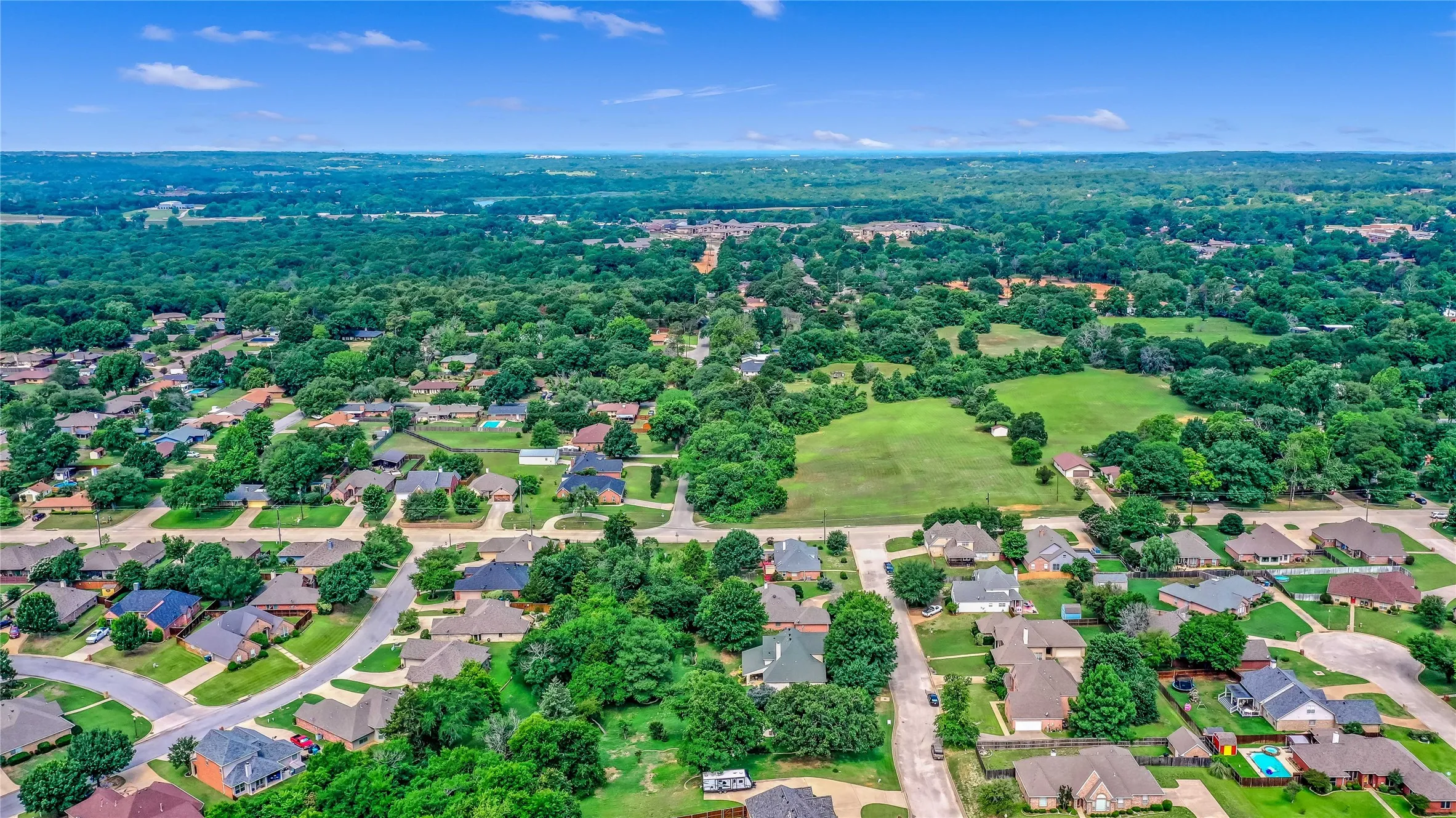 Aerial view of residential area featuring a golf club and a tree filled landscape