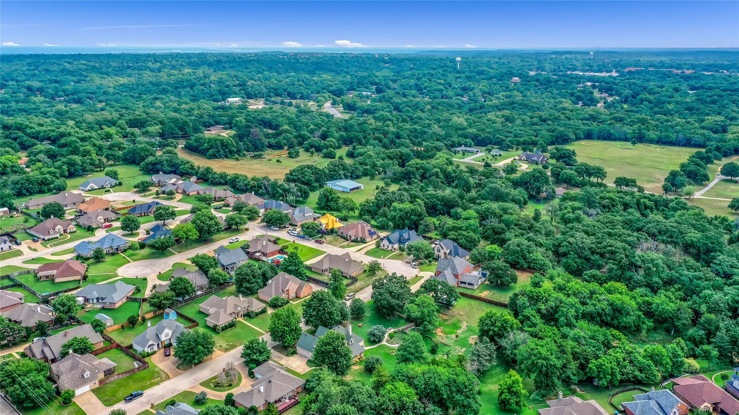 Aerial overview of property's location featuring nearby suburban area and a forest