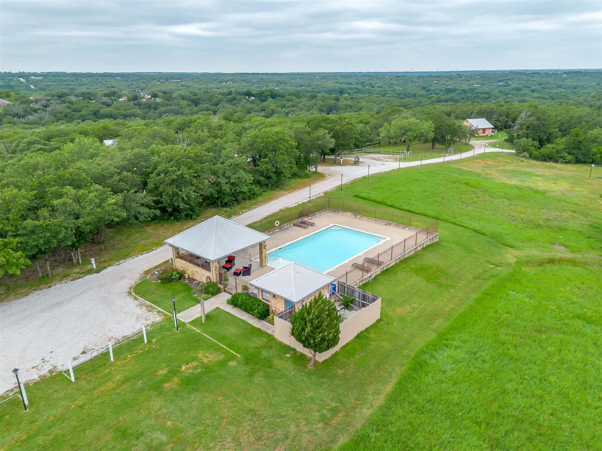 Aerial view of a pool and a heavily wooded area