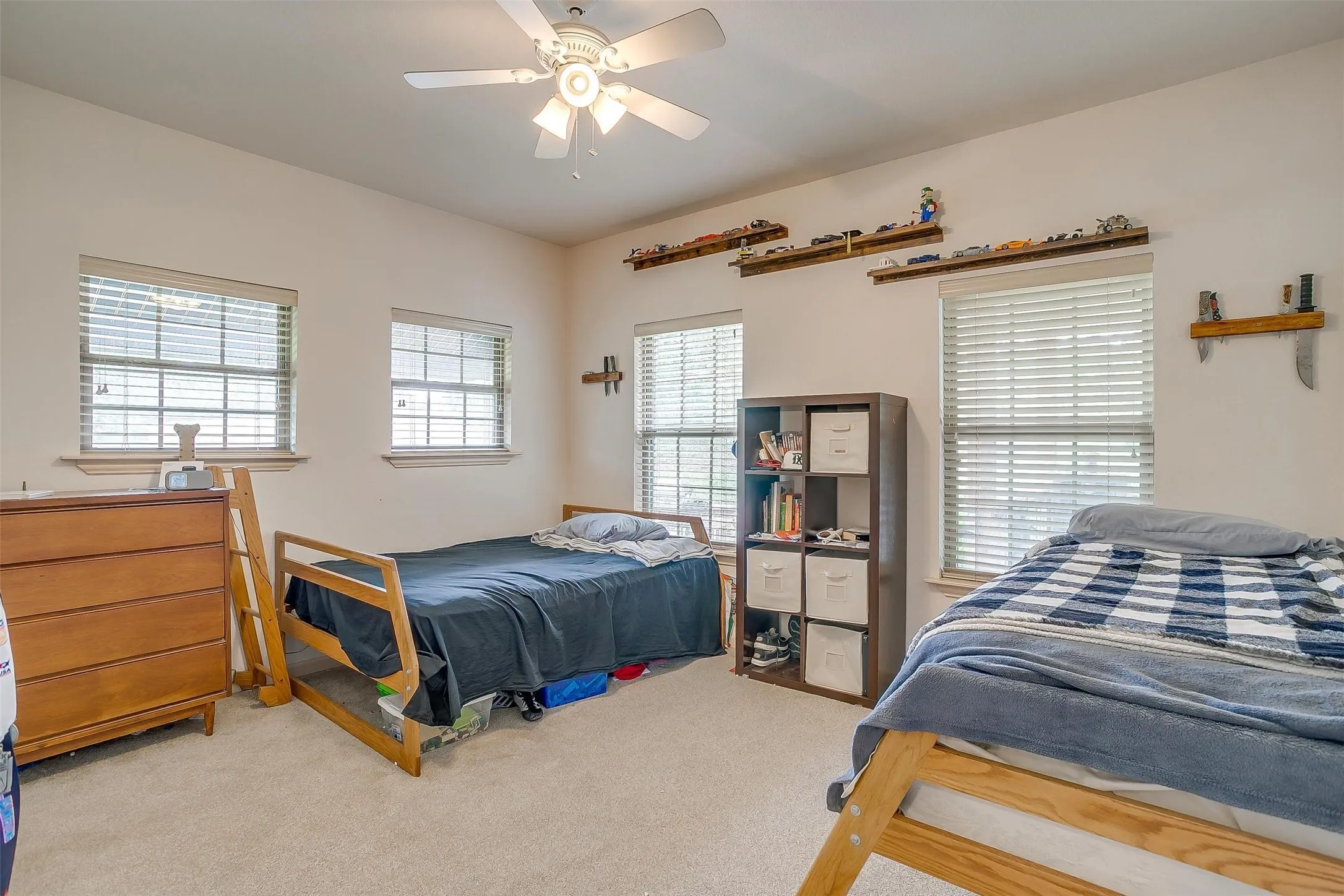 1 of 2 guest bedroom with light carpet and a ceiling fan