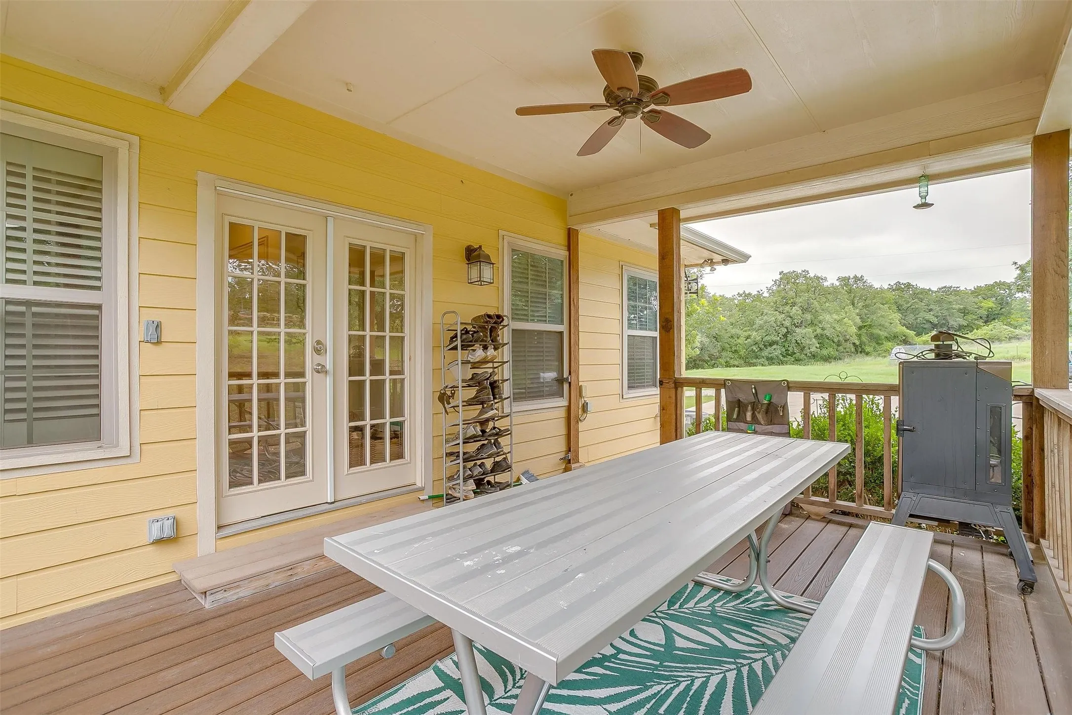 Main residence covered porch featuring a ceiling fan, outdoor dining space, french doors as main entry into home.