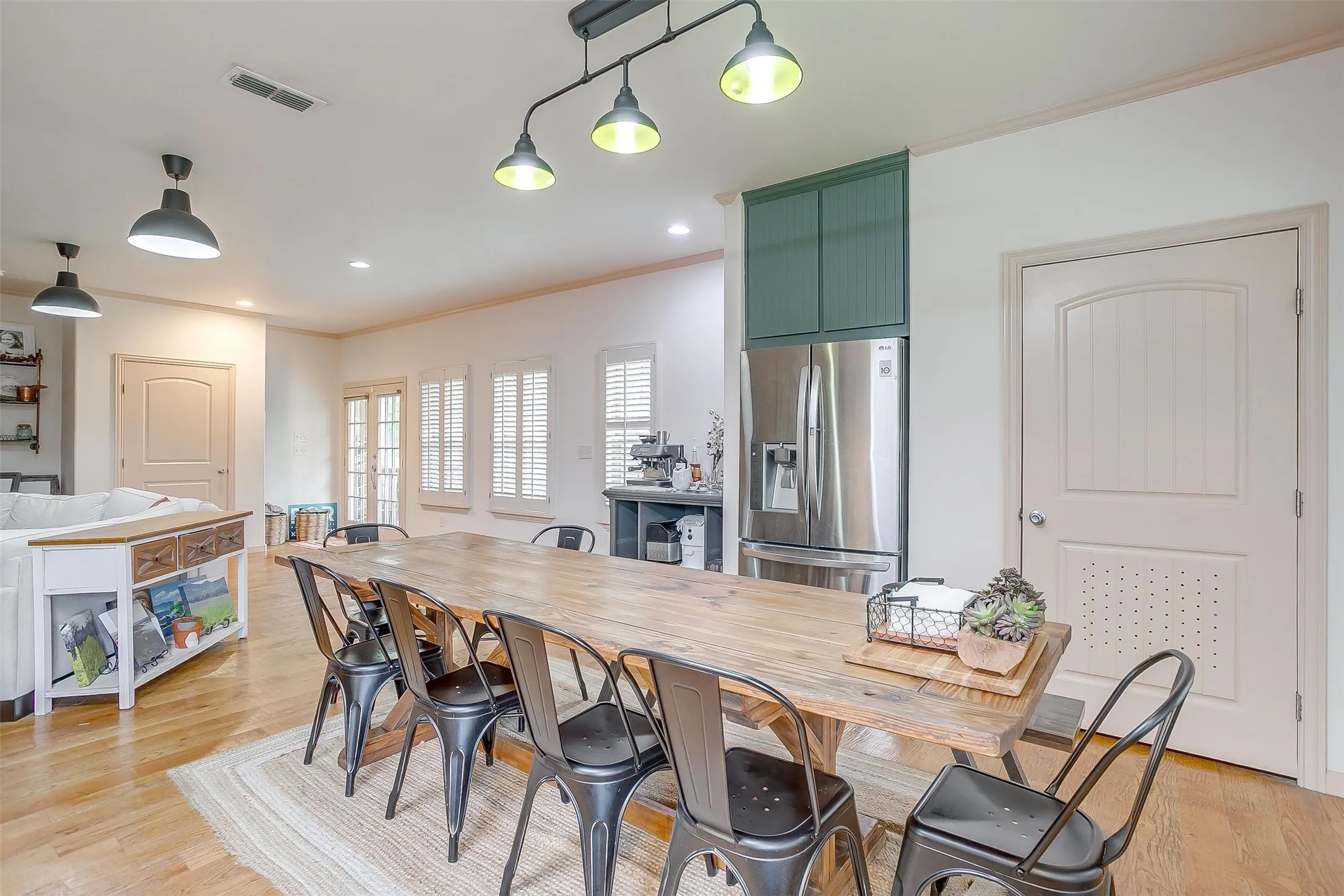 Kitchen featuring stainless steel fridge, crown molding, light wood-style flooring, recessed lighting, and decorative light fixtures