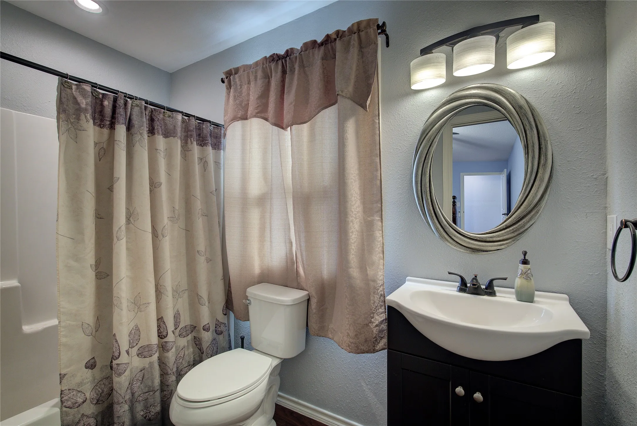 Full bathroom with shower / bath combo with shower curtain, vanity, and toilet