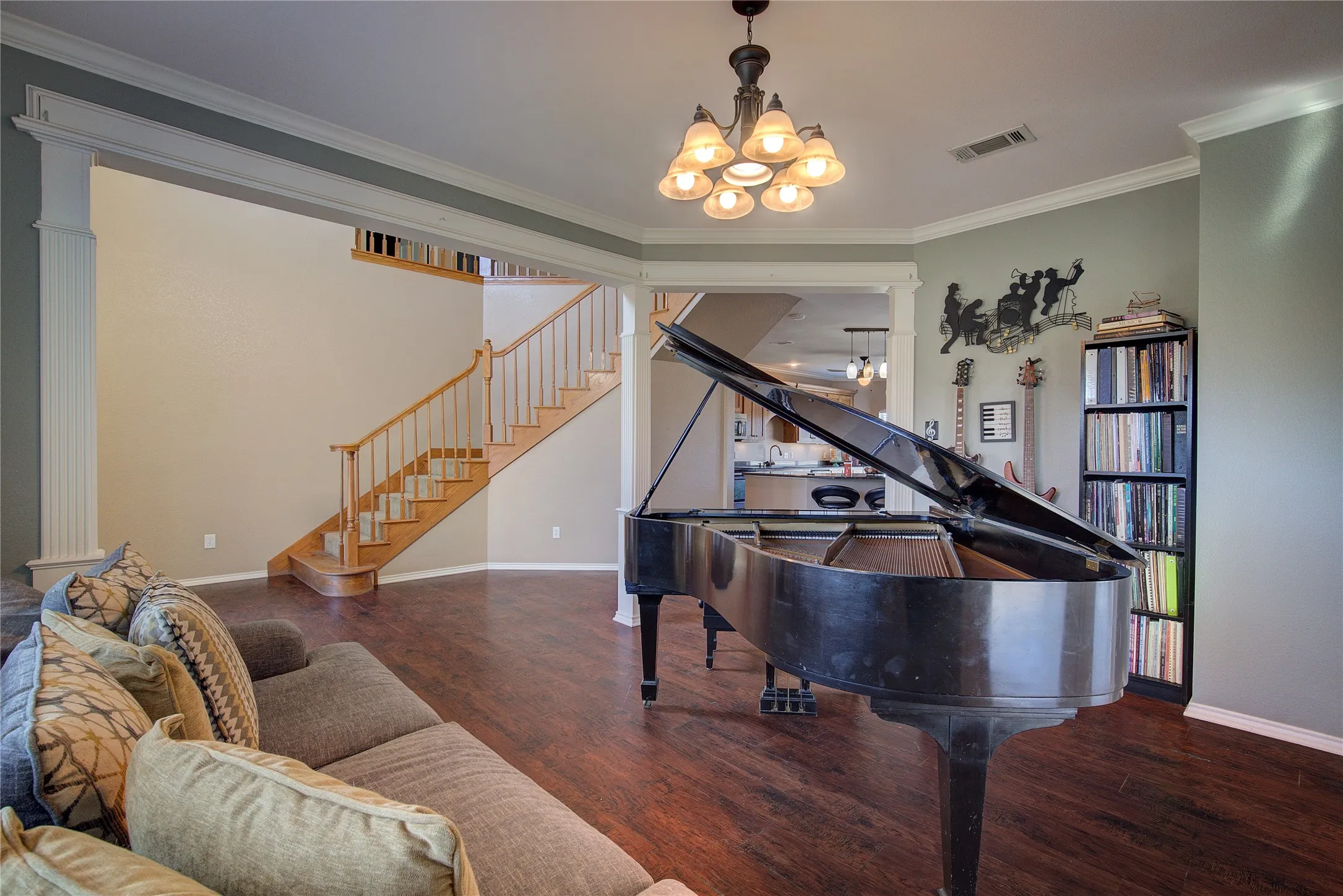 Living area with dark hardwood / wood-style floors, crown molding, and a chandelier