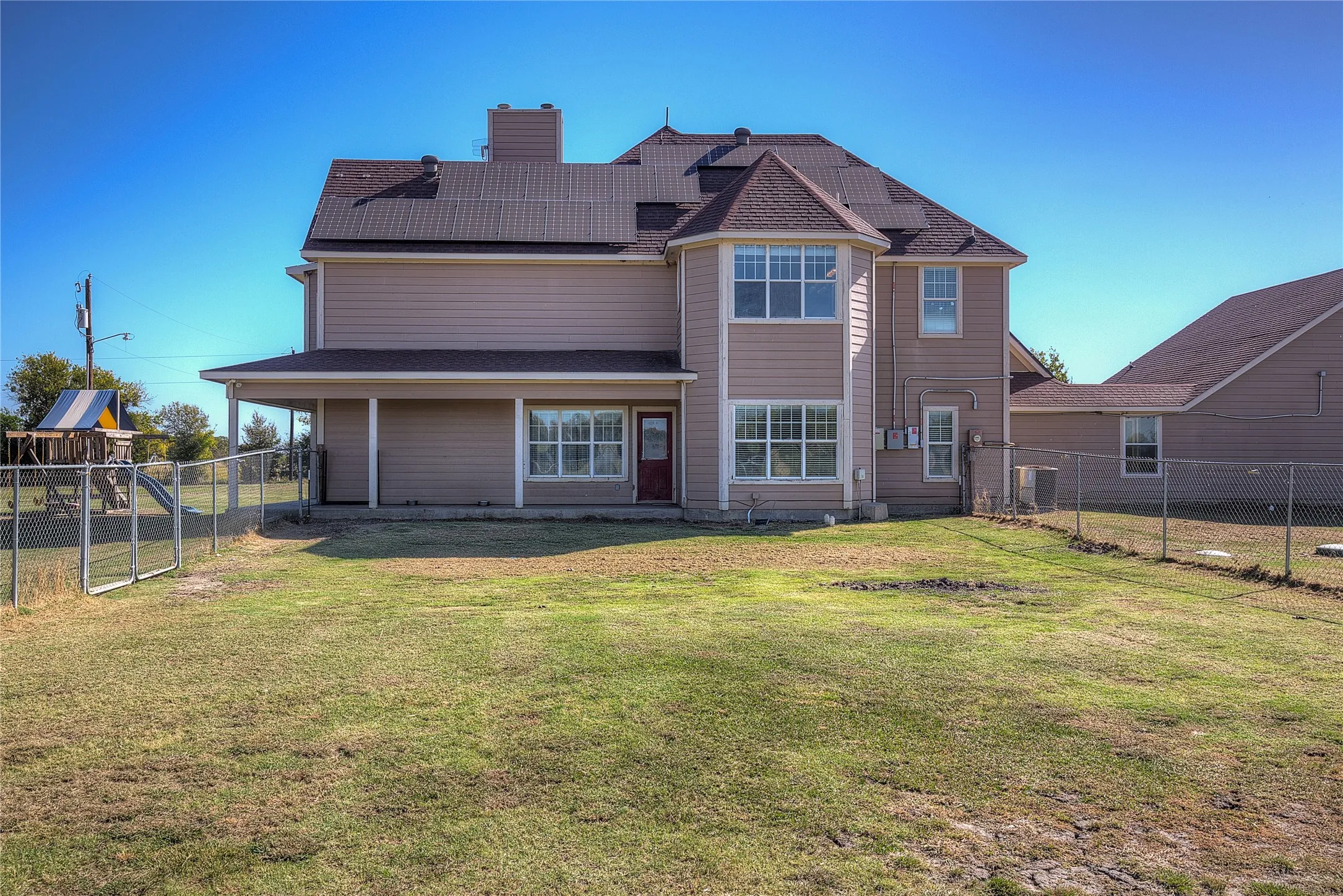 Rear view of property with a yard and solar panels