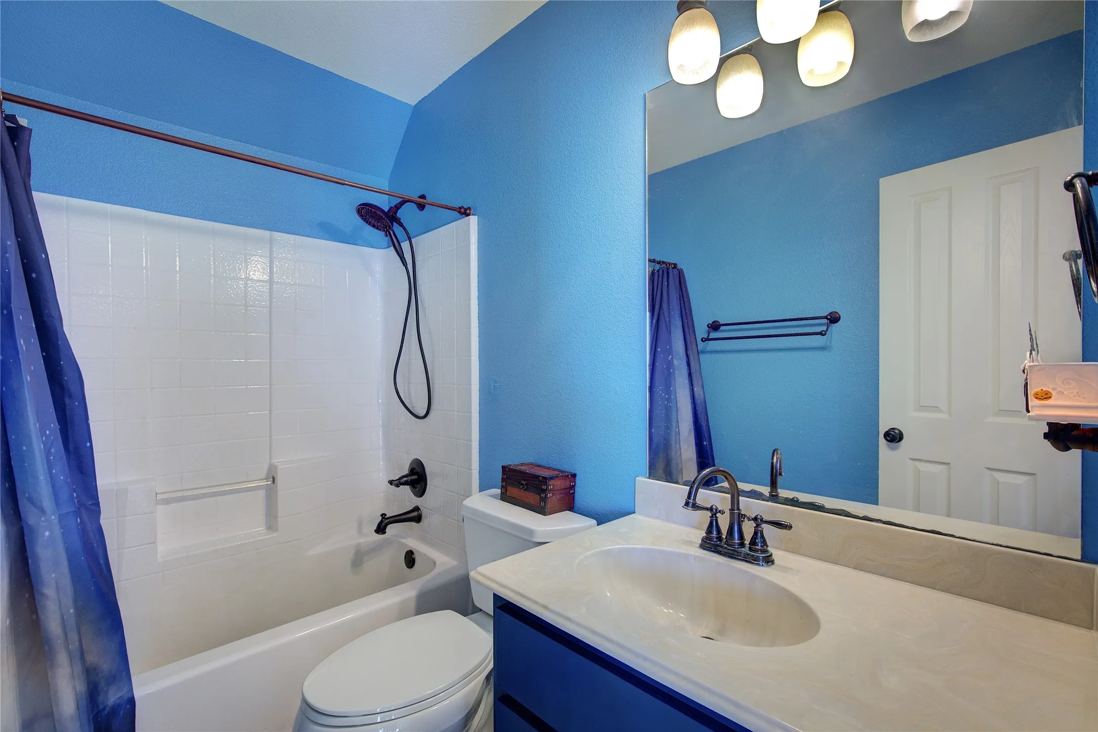 Full bathroom with vanity, toilet, shower / bathtub combination with curtain, and lofted ceiling