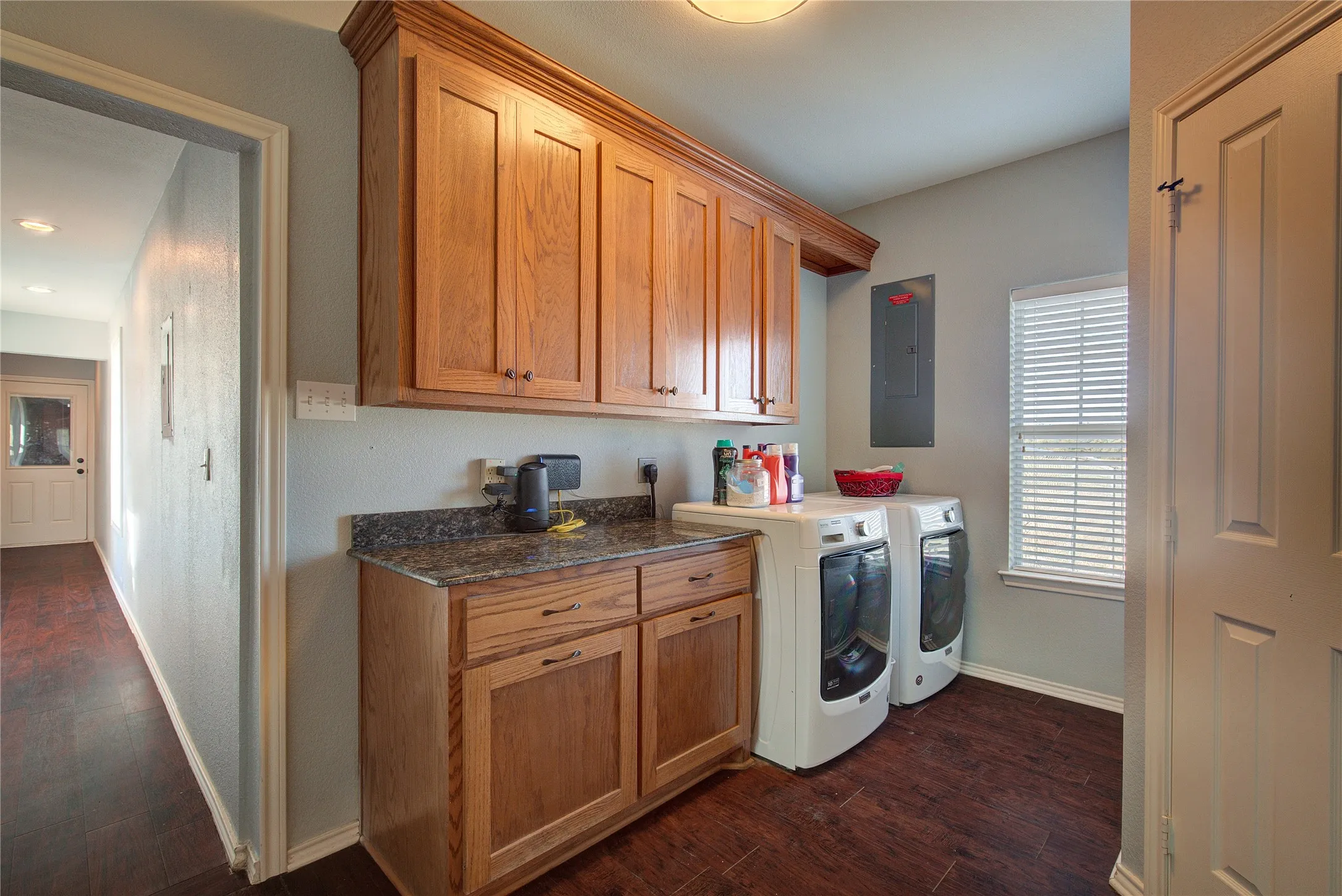 Laundry room featuring cabinets, dark hardwood / wood-style flooring, separate washer and dryer, and electric panel