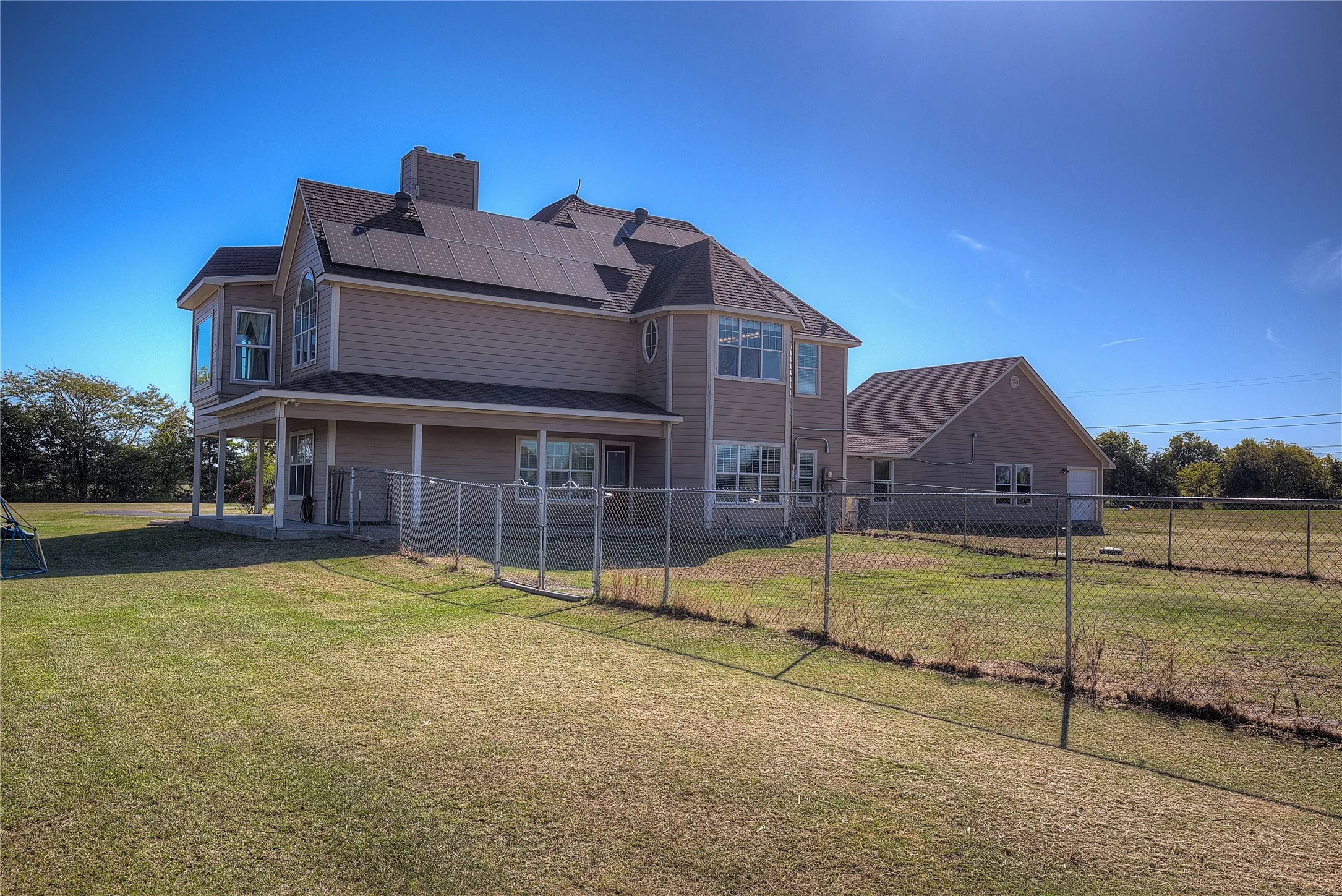 Rear view of house featuring solar panels and a yard