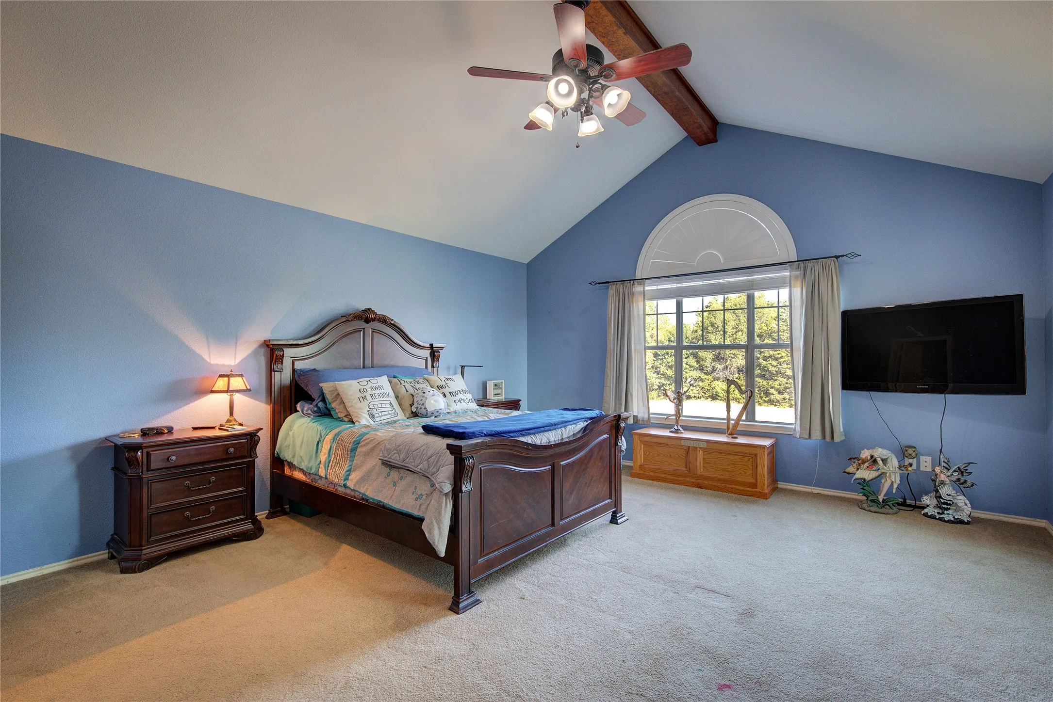 Bedroom with ceiling fan, beamed ceiling, light carpet, and high vaulted ceiling