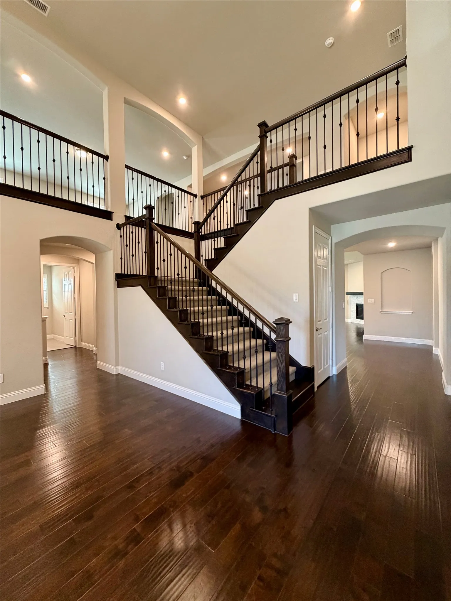 Unfurnished dining room featuring arched walkways, a towering ceiling, dark wood-style floors, recessed lighting, and stairway