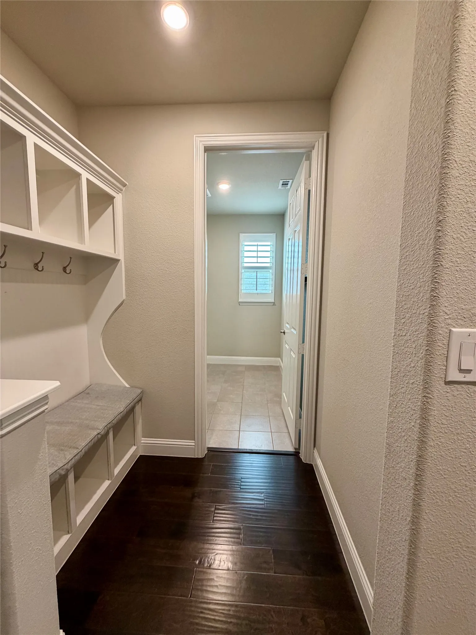 Mudroom with a textured wall and dark wood finished floors