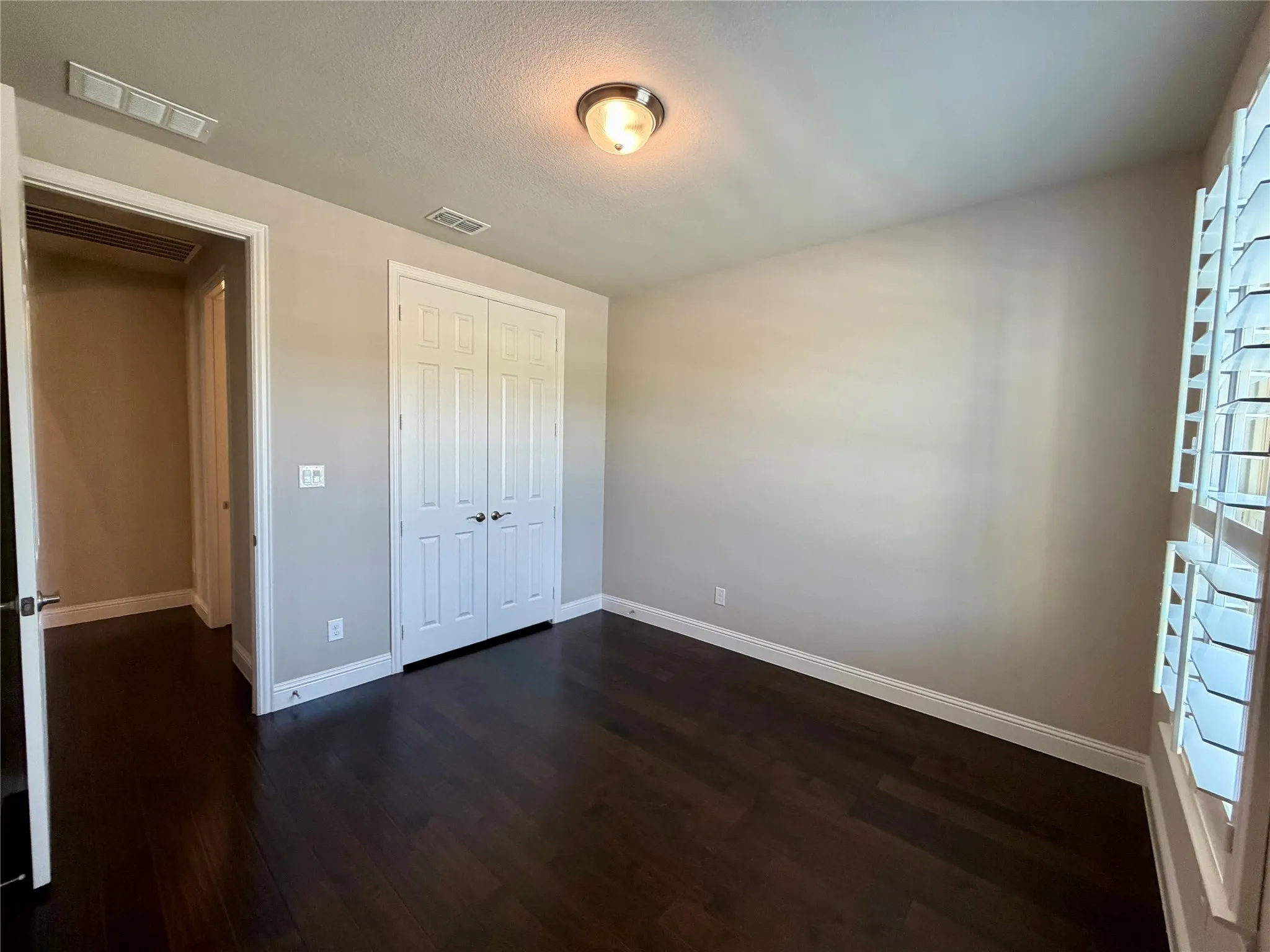 Unfurnished bedroom featuring dark wood-style flooring, a textured ceiling, and a closet