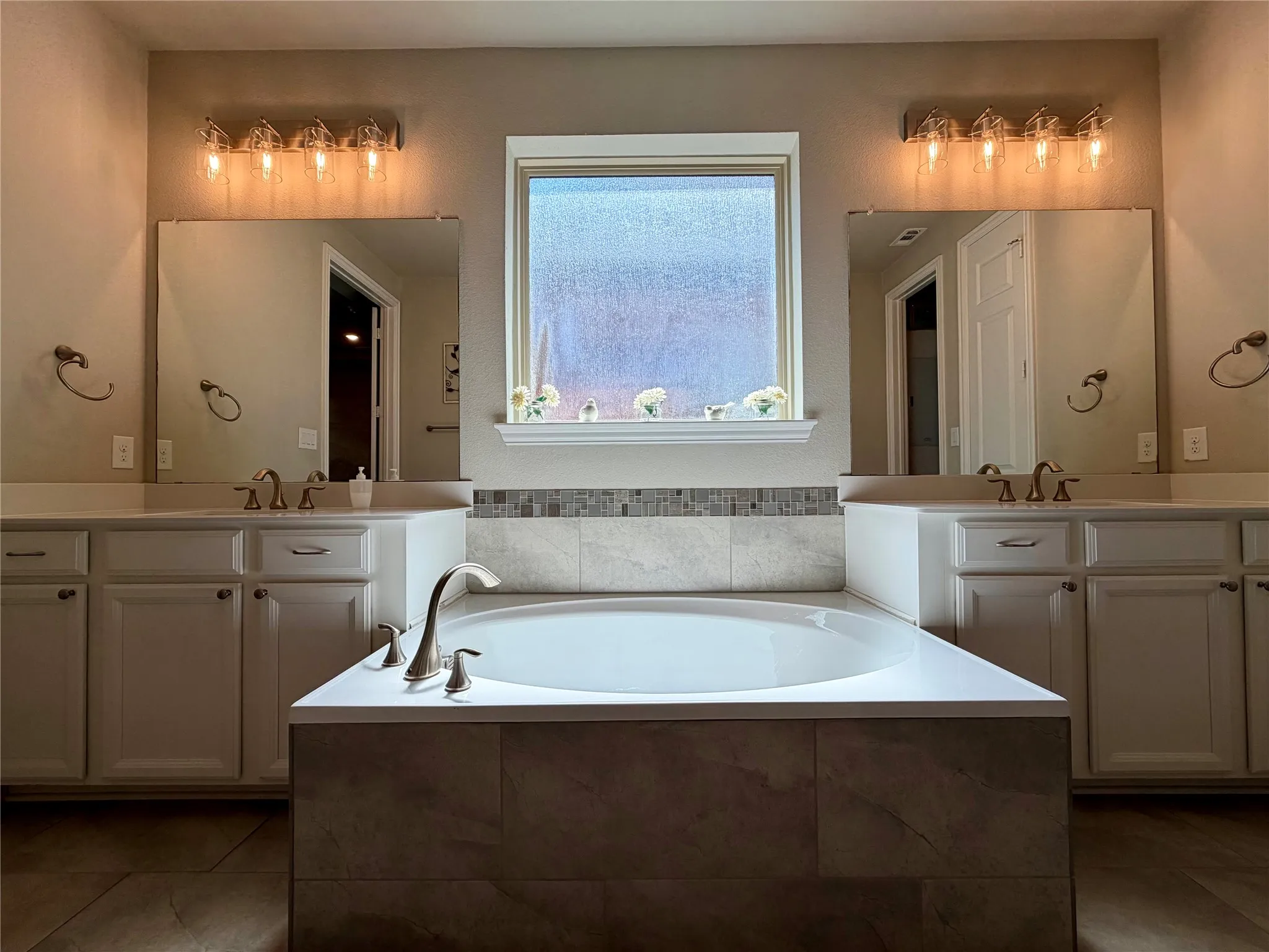Primary Bathroom with two vanities, a bath, and light tile patterned floors
