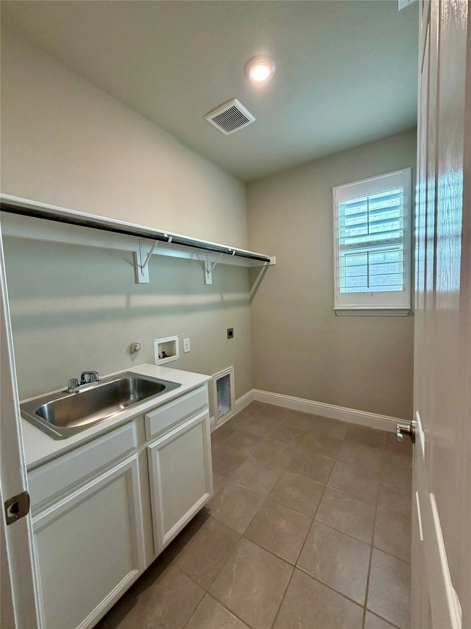 Washroom with light tile patterned floors, hookup for a washing machine, and electric dryer hookup