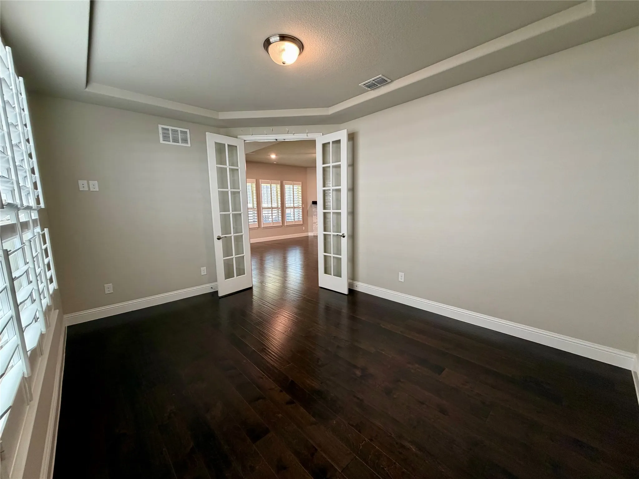 Office with french doors, a raised ceiling, and dark wood finished floors