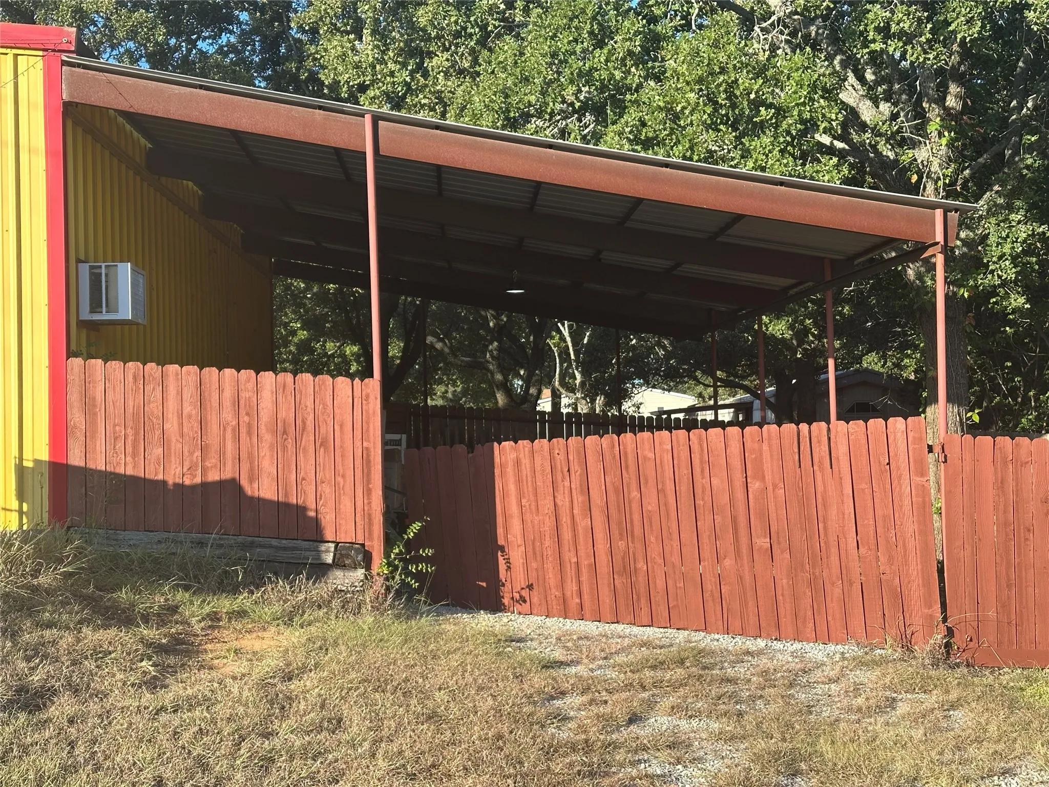 A fully fenced carport with a double wide gate