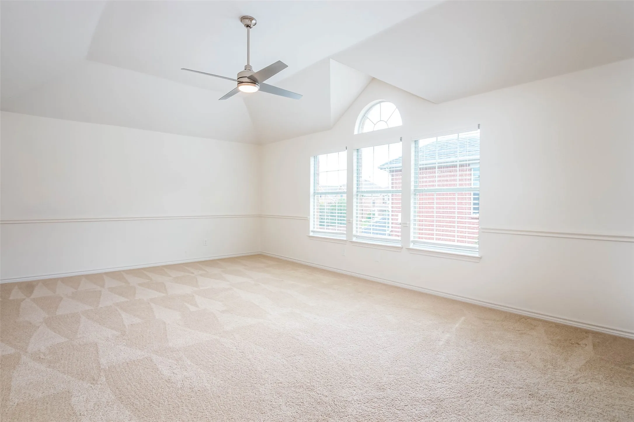 Spare room featuring vaulted ceiling, light carpet, and ceiling fan
