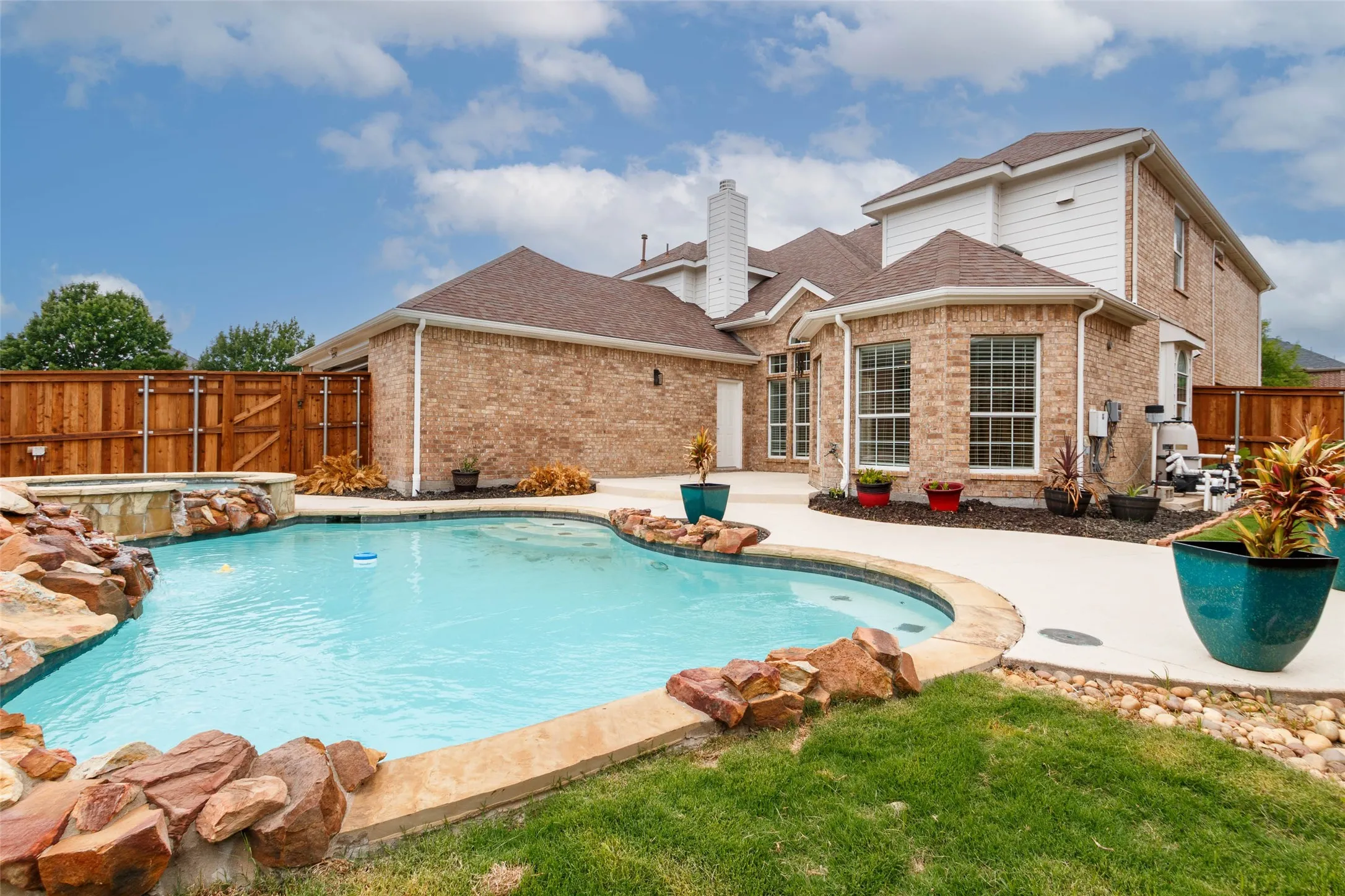 View of swimming pool with a fenced backyard, a pool with connected hot tub, and a patio area