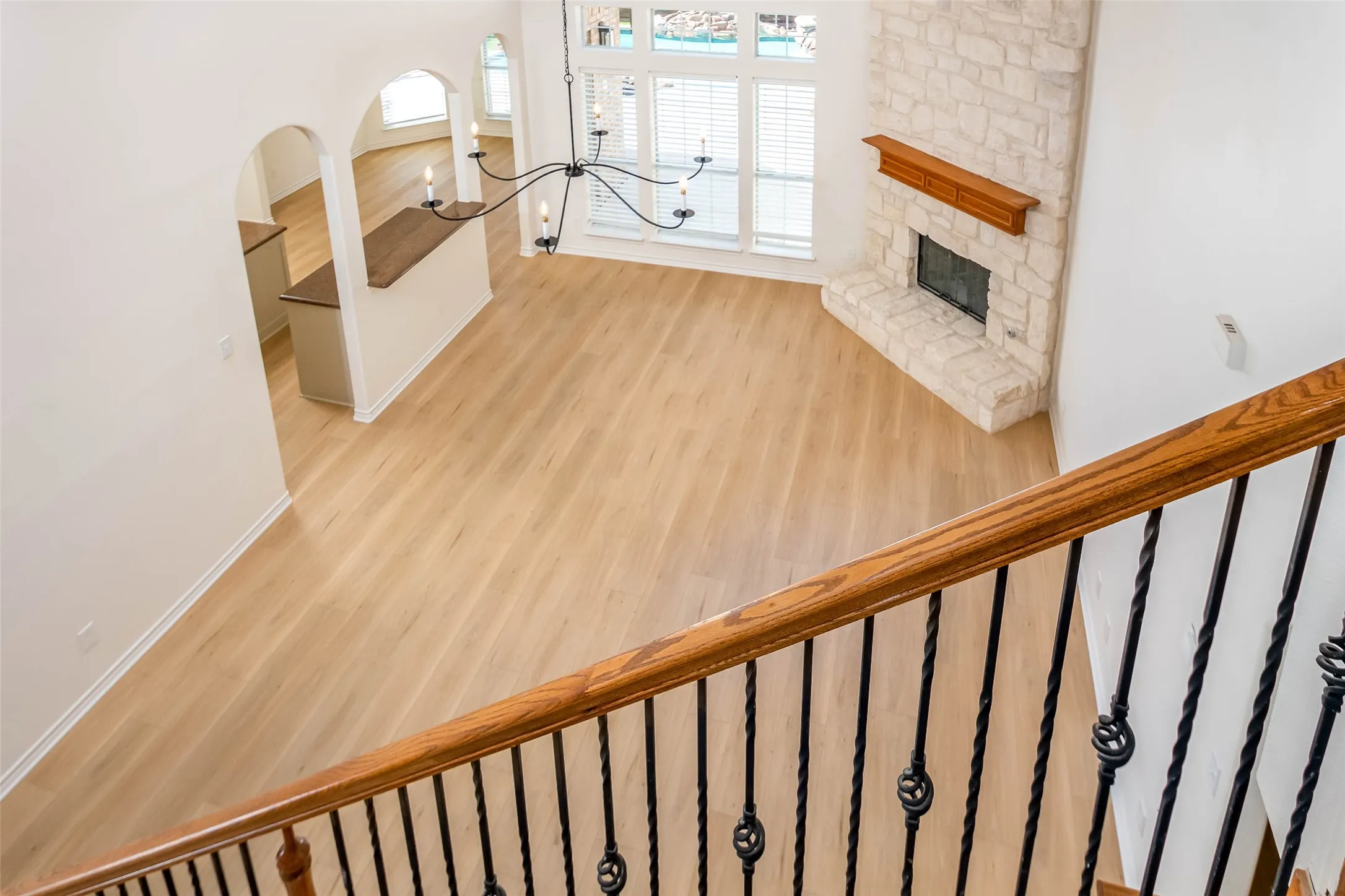 Stairs featuring wood finished floors, a chandelier, and a stone fireplace