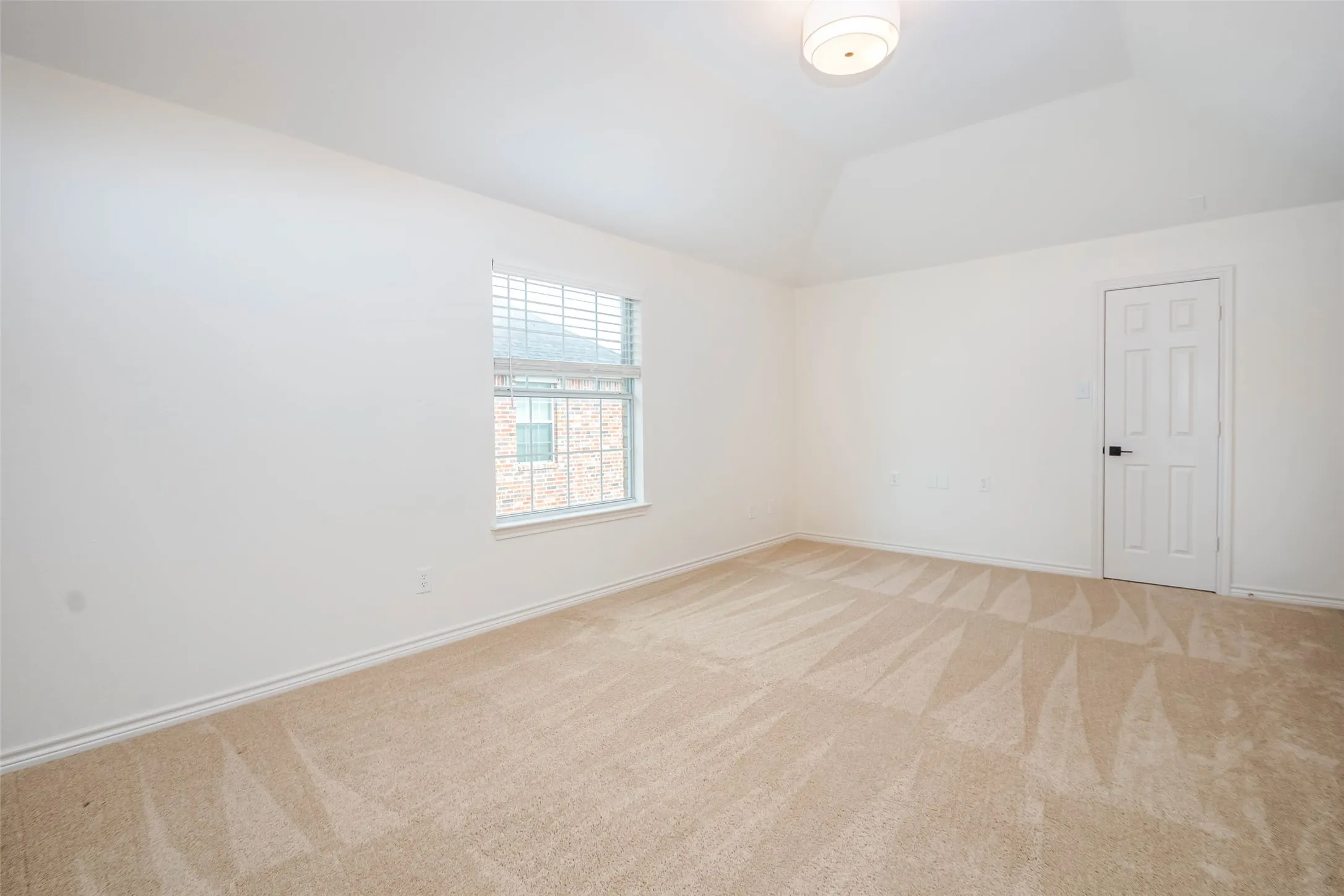 Carpeted empty room with baseboards and lofted ceiling