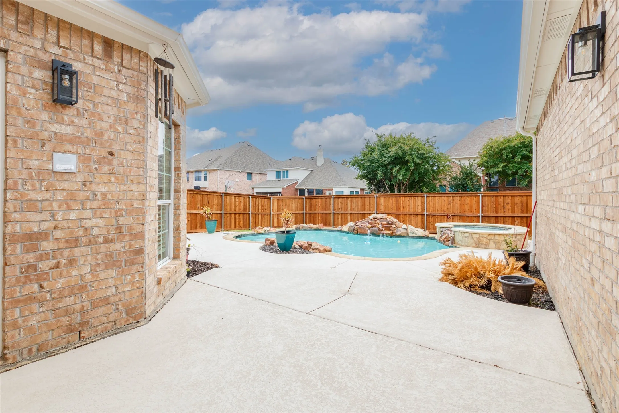 View of pool with a patio area, a fenced backyard, and a pool with connected hot tub