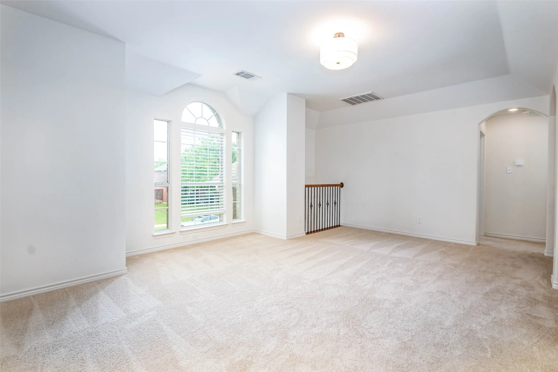 Unfurnished room featuring arched walkways and light carpet
