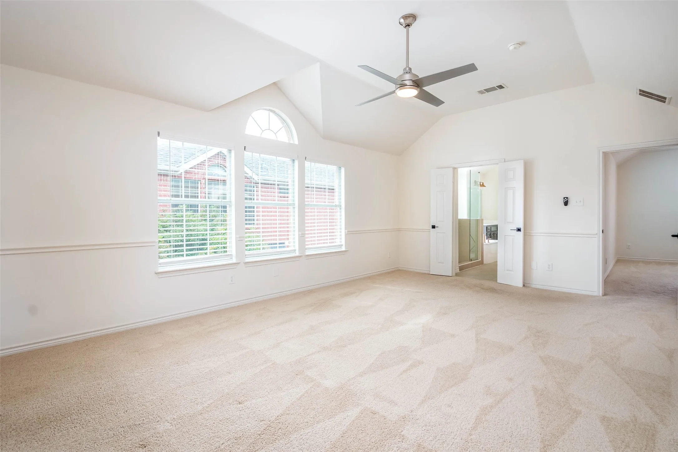 Unfurnished bedroom with light colored carpet, ceiling fan, and high vaulted ceiling