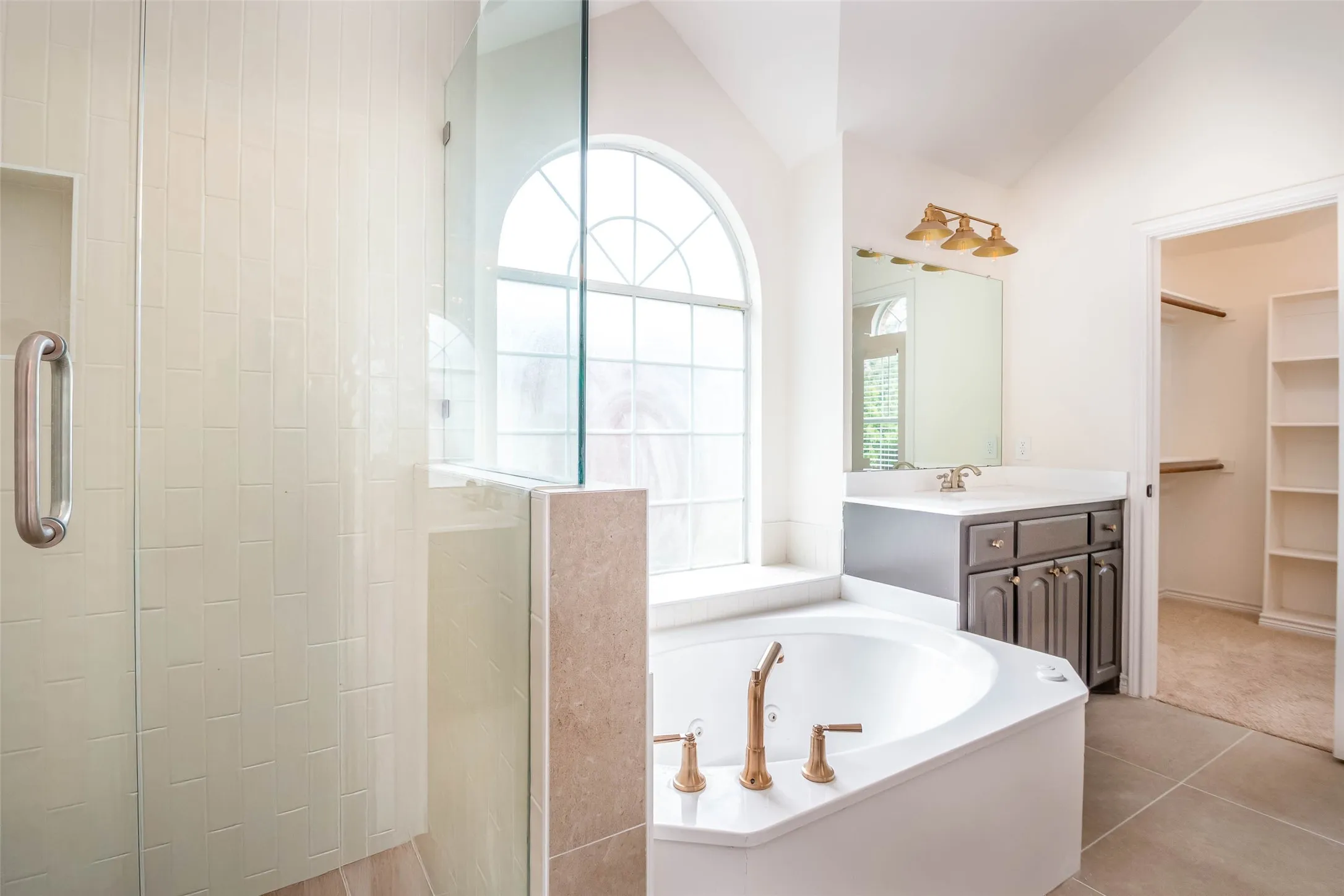 Bathroom with vanity, a garden tub, walk in shower, a spacious closet, and vaulted ceiling