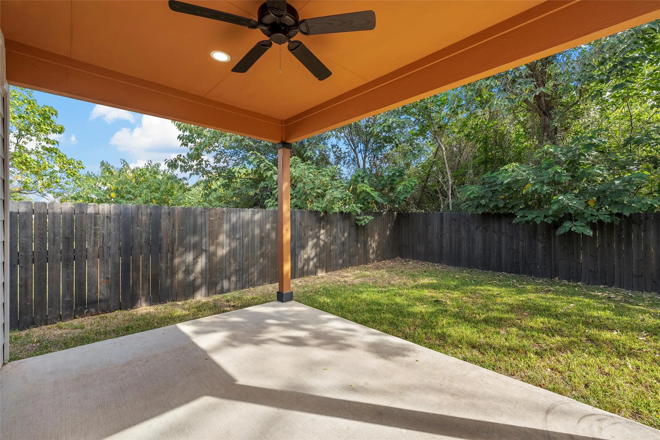 Fenced backyard featuring a patio area and a ceiling fan
