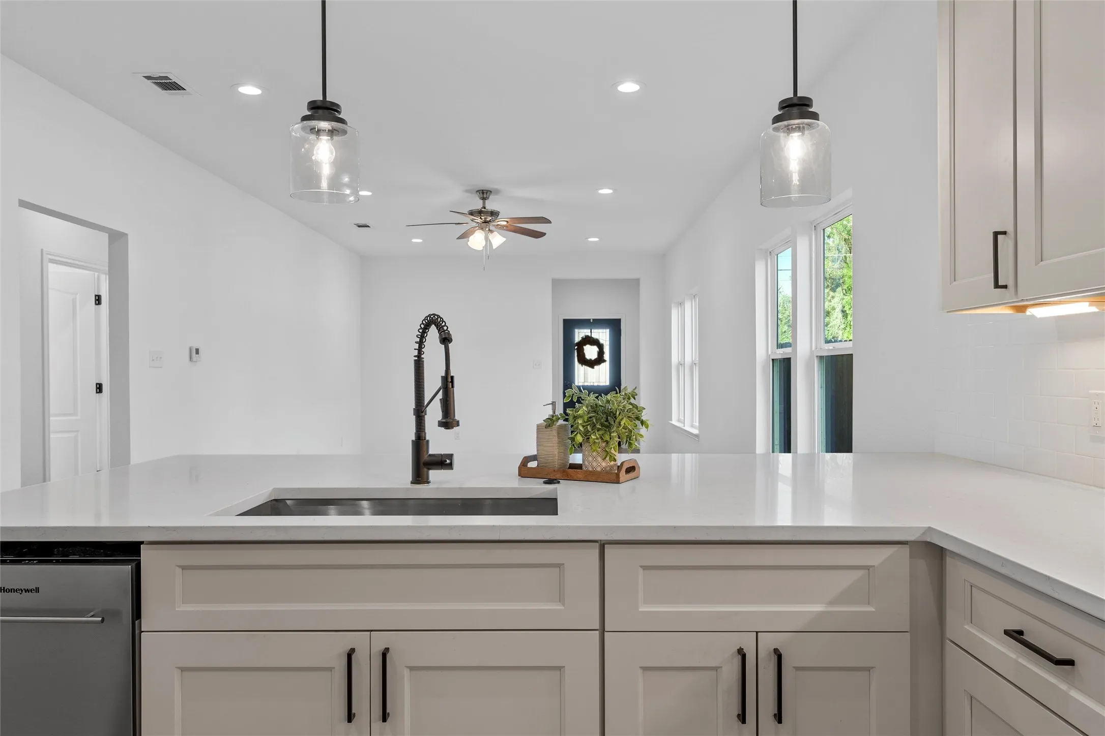 Kitchen featuring light quartz counters, decorative light fixtures, recessed lighting, backsplash, and white cabinets