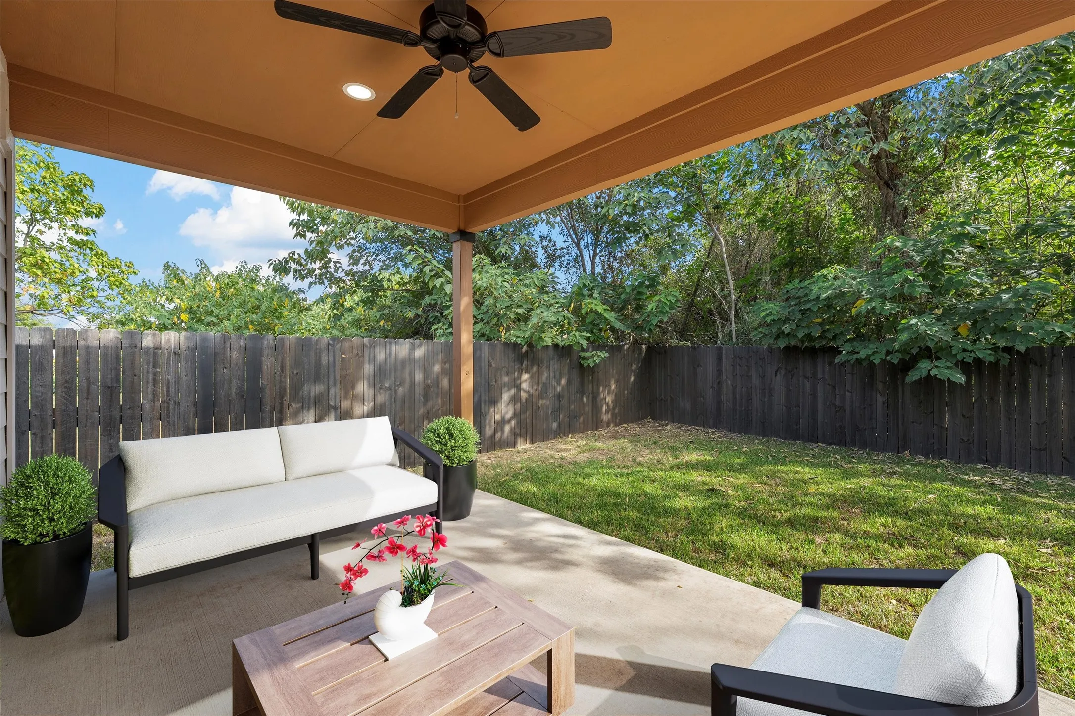 Picture Virtually Staged. Fenced backyard with an outdoor hangout area, a patio area, and ceiling fan