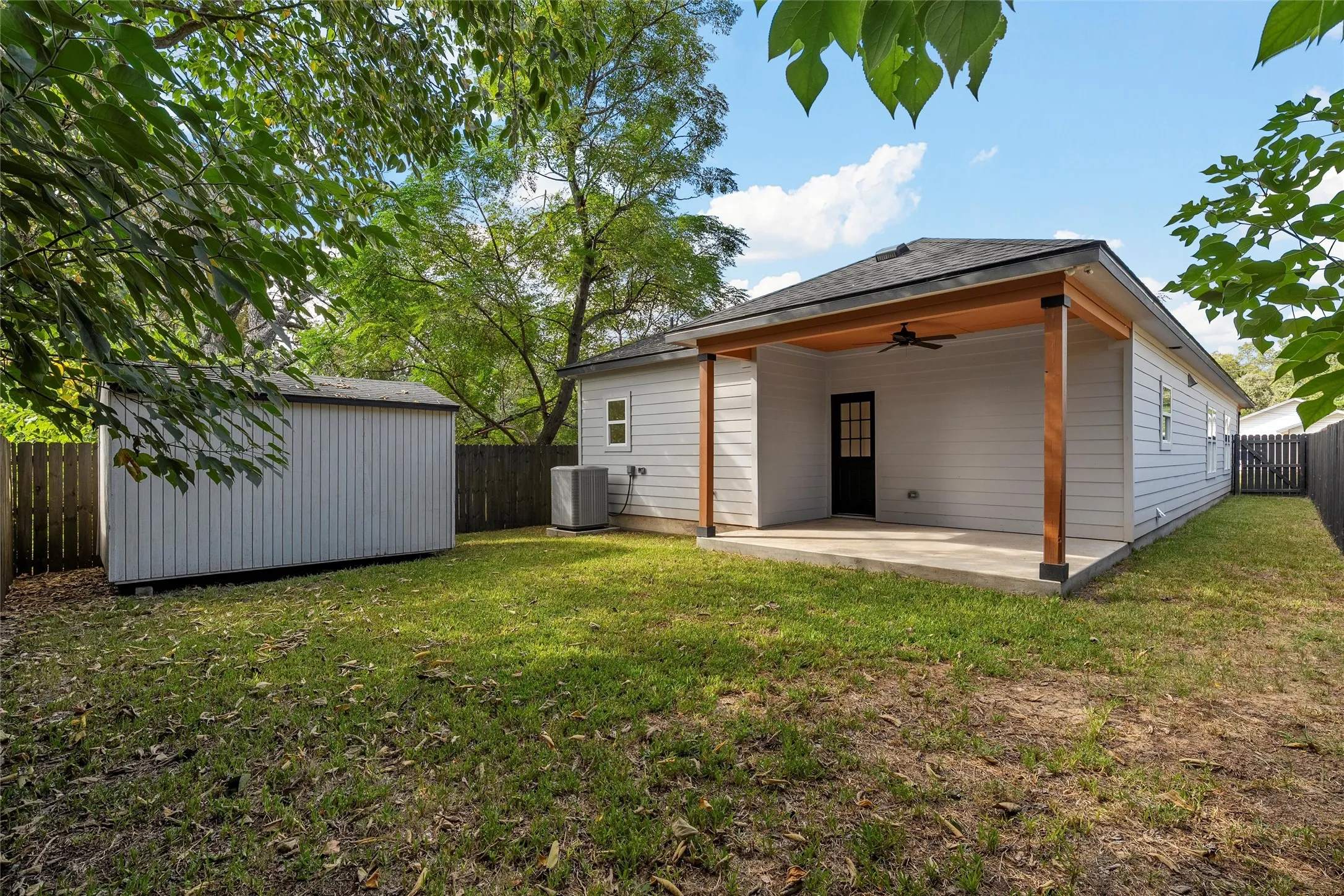 Back of property featuring a ceiling fan, a patio, a fenced backyard, and a shed