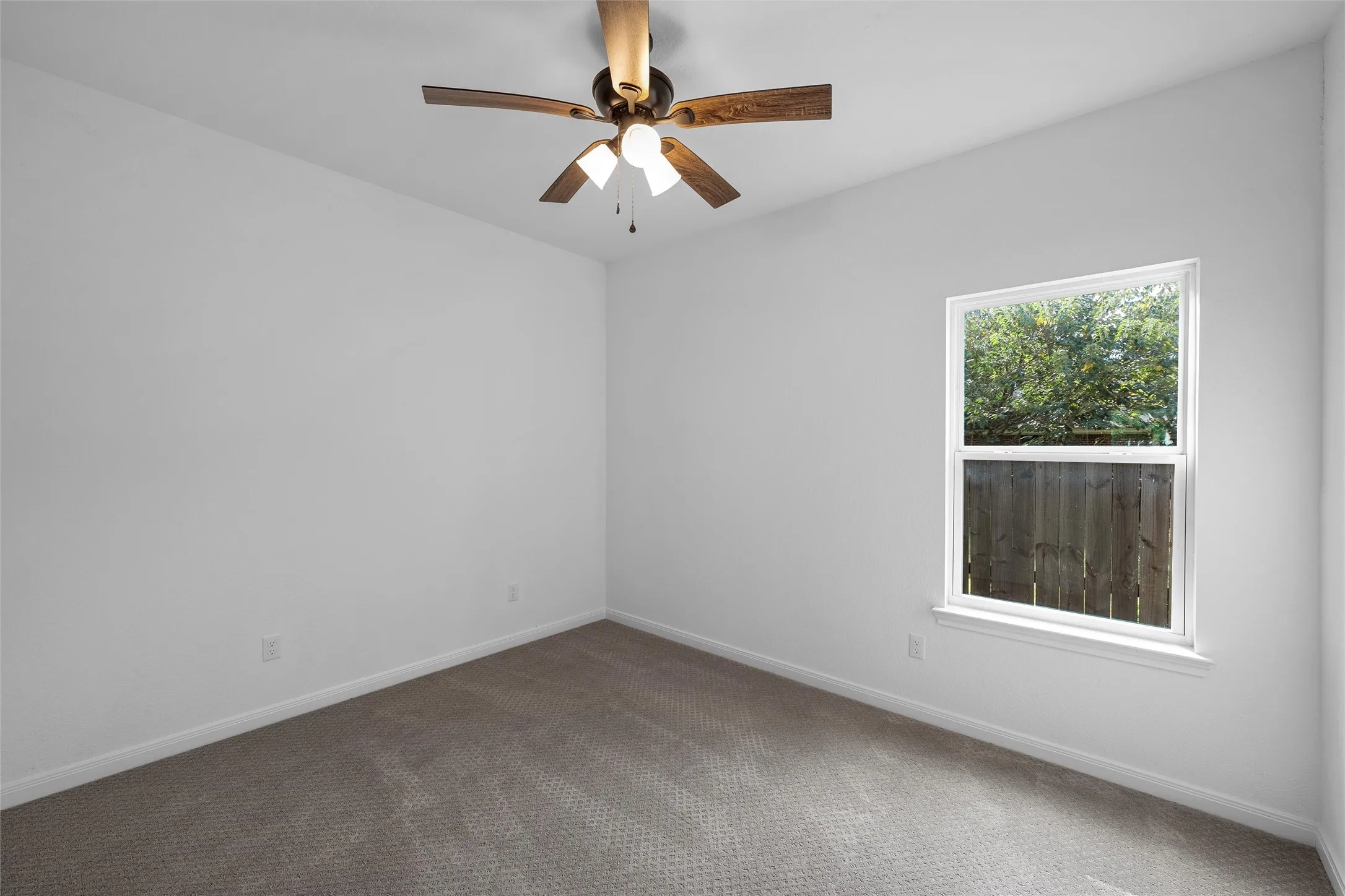 Carpeted empty room featuring baseboards and ceiling fan
