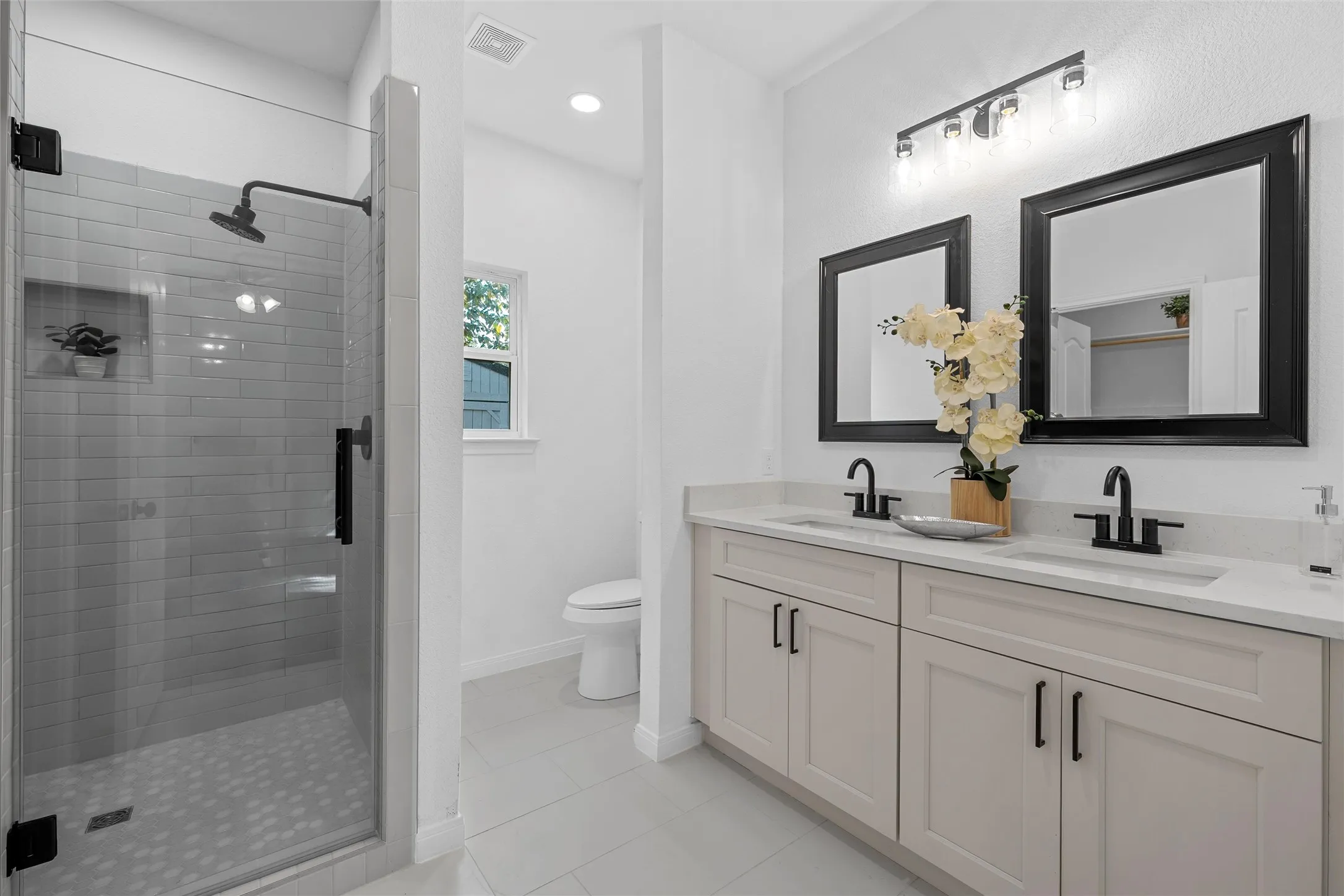 Full bath featuring a stall shower, double vanity, and light tile patterned floors