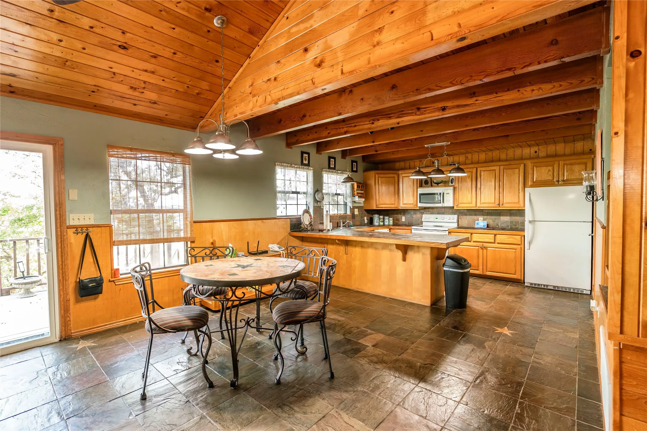 Dining area featuring wooden walls, a wainscoted wall, and wood ceiling